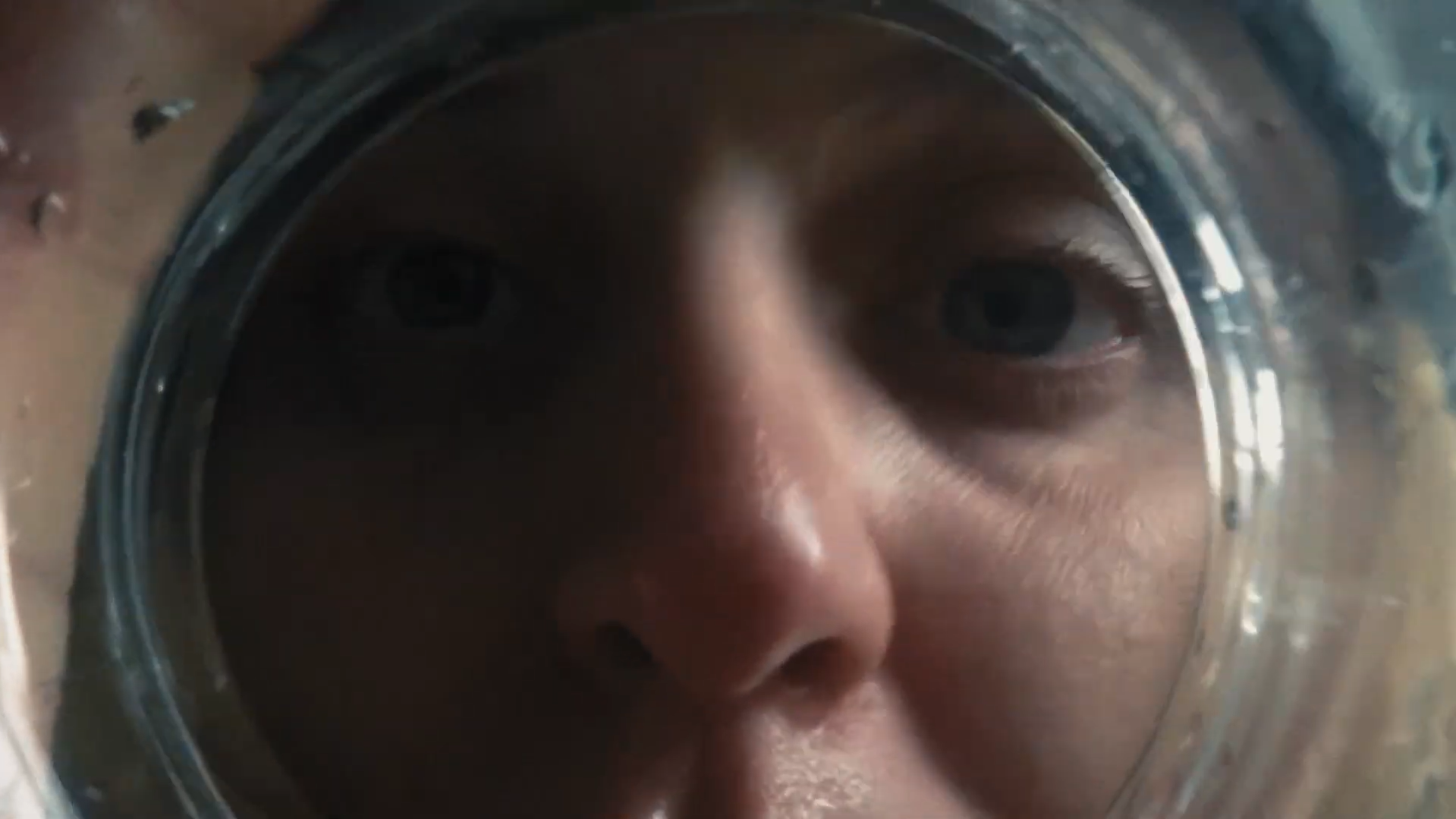 Person’s face seen close-up through a transparent glass surface.