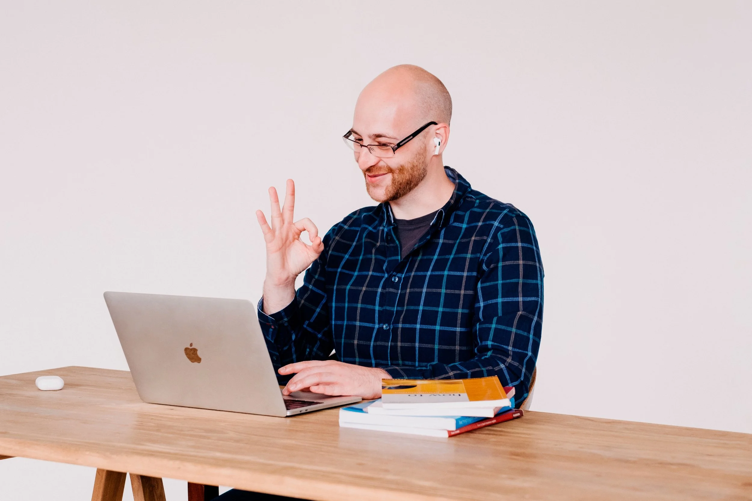 Jamie sitting in front of a laptop making an "ok" gesture with his hand.