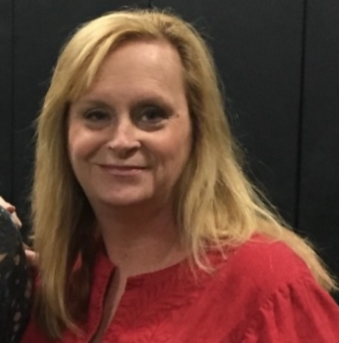 A woman with blonde hair wearing a red top smiling at the camera.