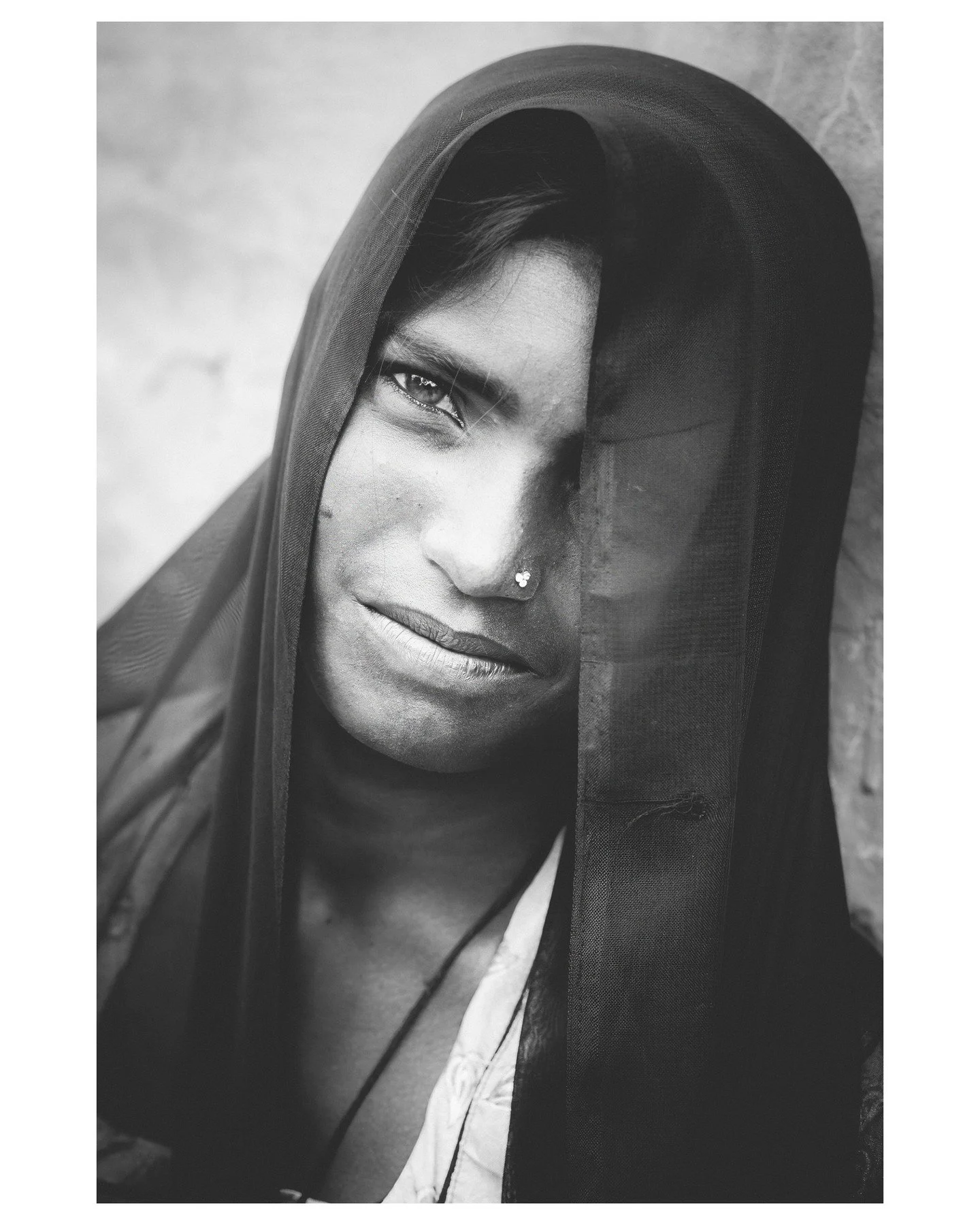 𝐑𝐀𝐉𝐀𝐒𝐓𝐇𝐀𝐍 • Her face is partly hidden, yet her eyes reveal everything. The veil softens her features, 𝐛𝐮𝐭 𝐡𝐞𝐫 𝐠𝐚𝐳𝐞 𝐢𝐬 𝐝𝐢𝐫𝐞𝐜𝐭 — intense, unflinching, and filled with quiet strength. In Rajasthan, the veil is both