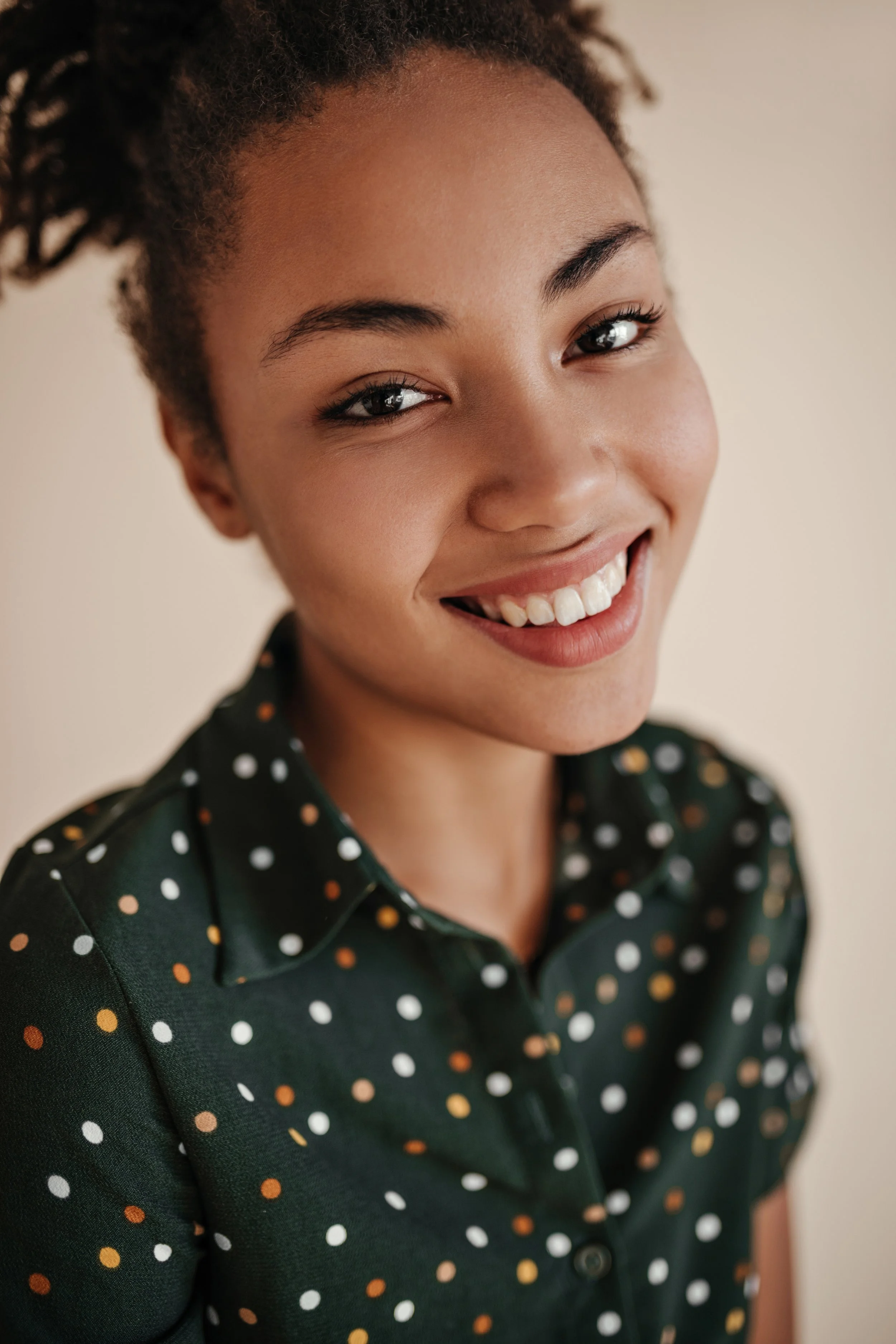 Young woman with curly hair smiling, studio portrait