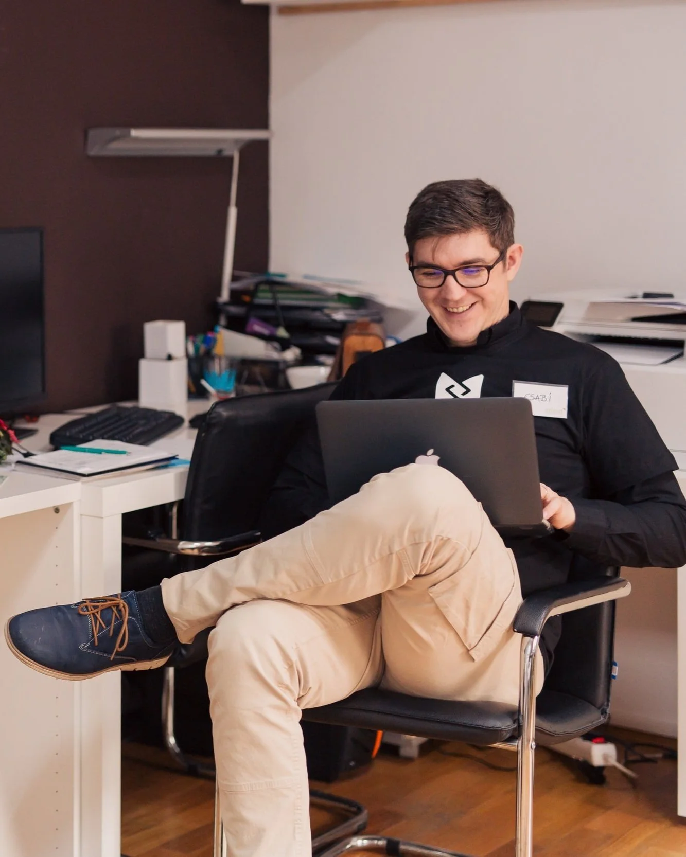 Man sitting with a laptop on his lap, smiling