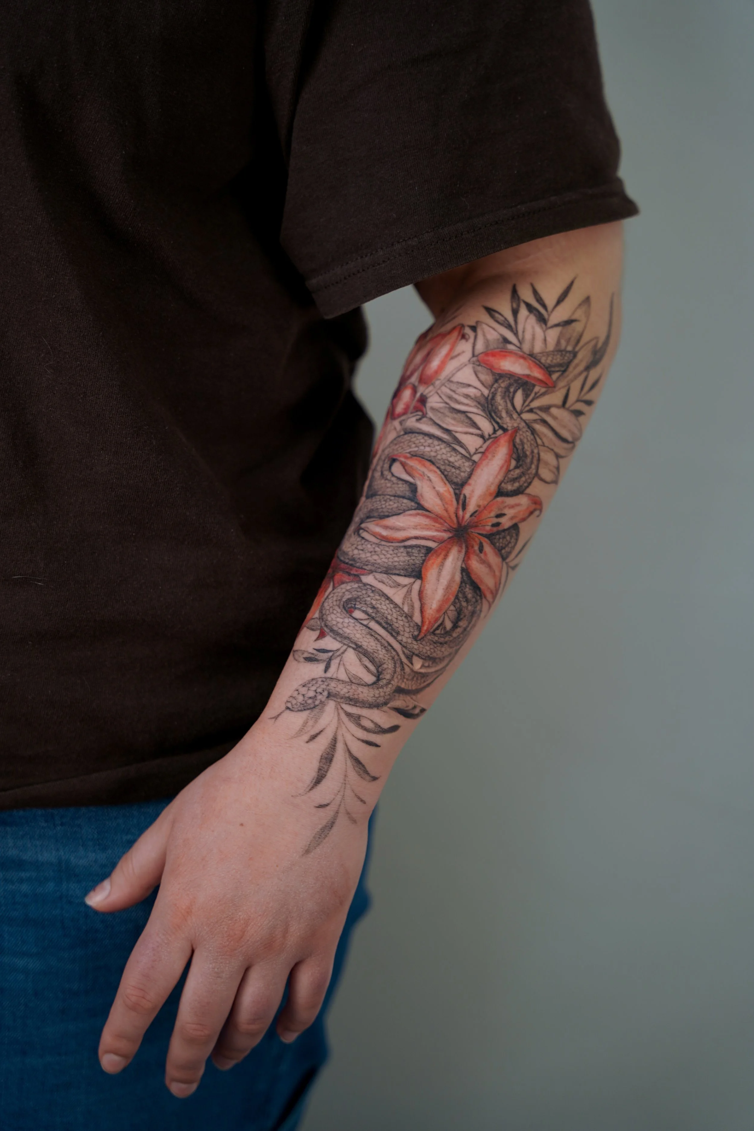 Snake and lily scar cover-up tattoo on the forearm