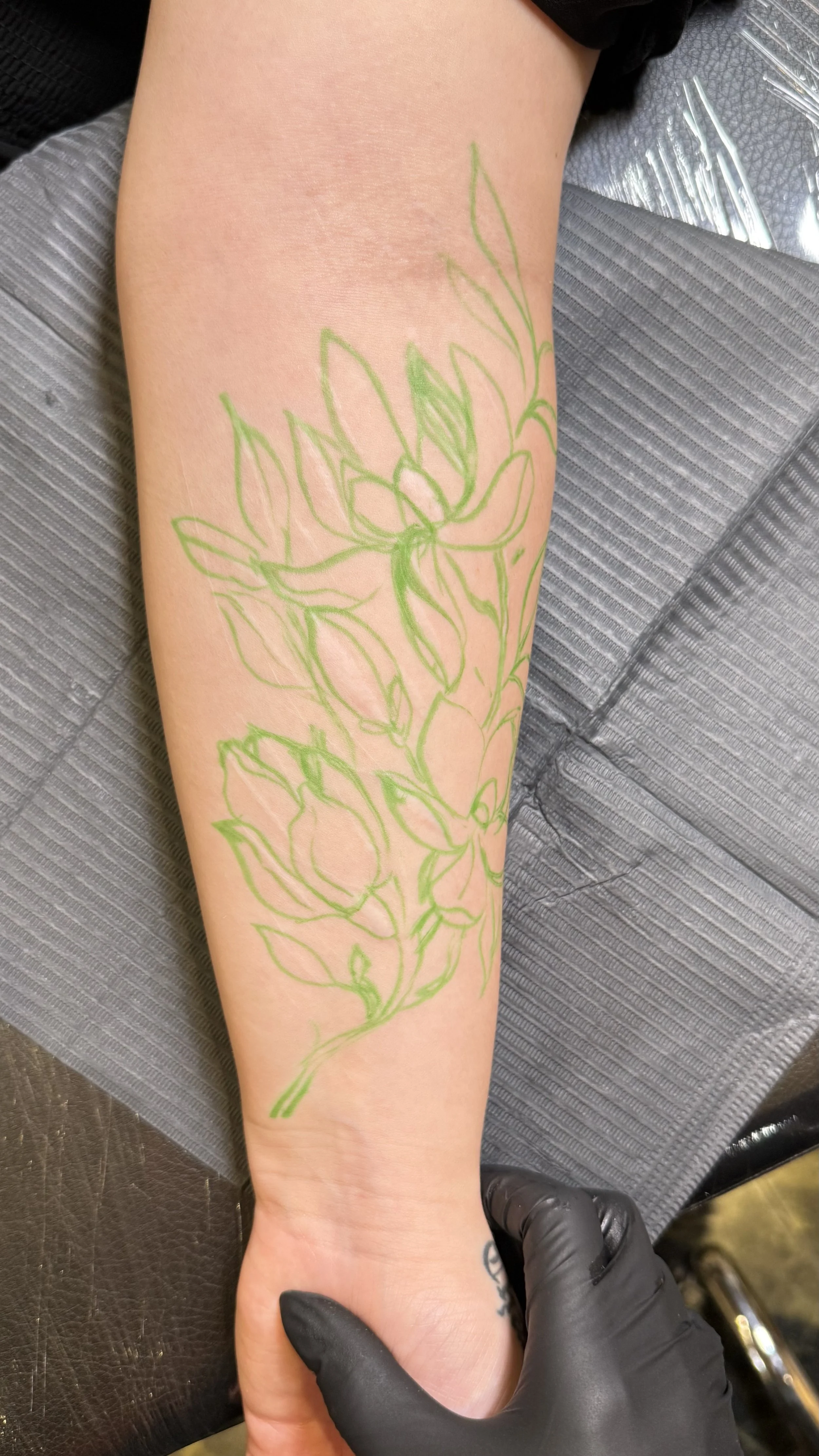Custom botanical stencil placed to follow the natural direction of the scars on the forearm.