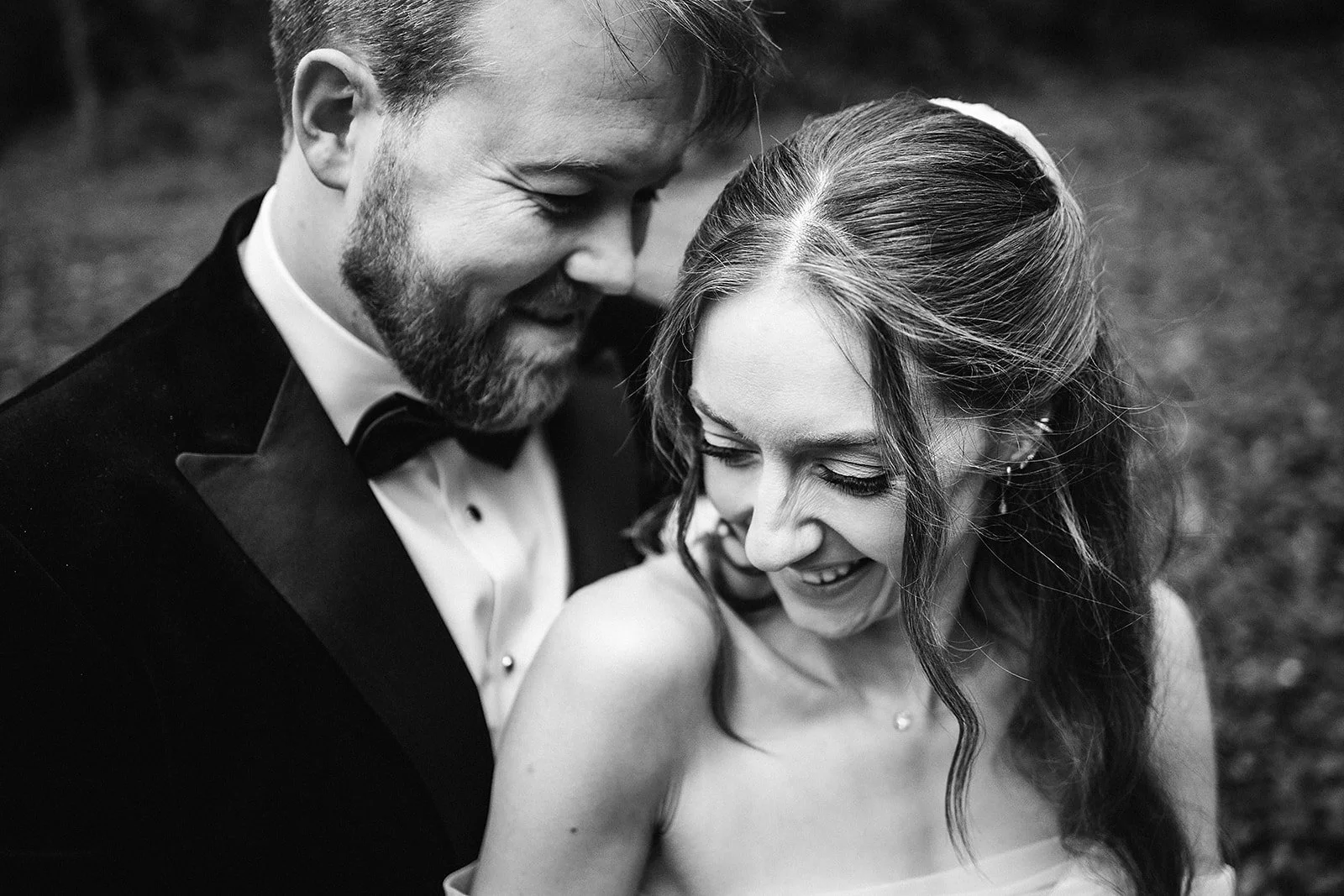 A smiling bride and groom sharing a joyful moment at their wedding, close-up black and white photograph.