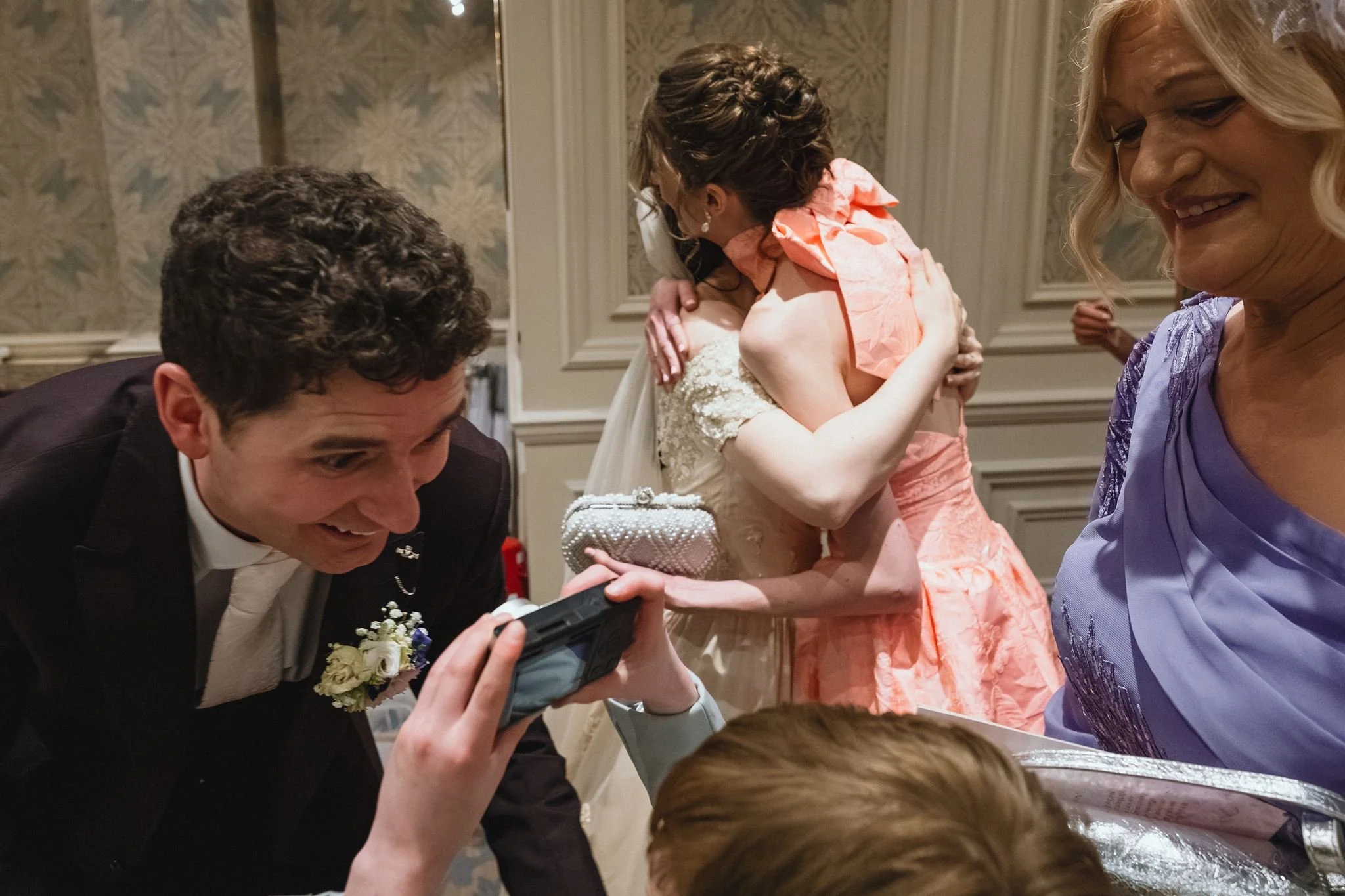 People hugging and celebrating at a social gathering, possibly a wedding or special event.
