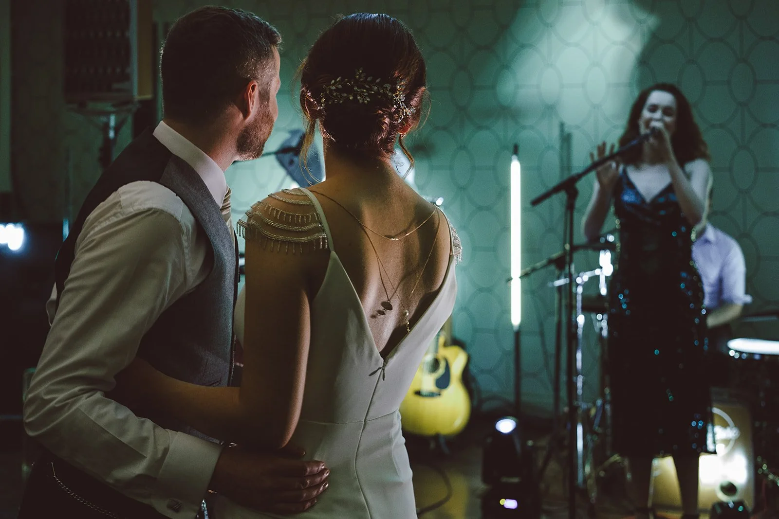 Couple in formal attire dancing, with a band performing in the background.