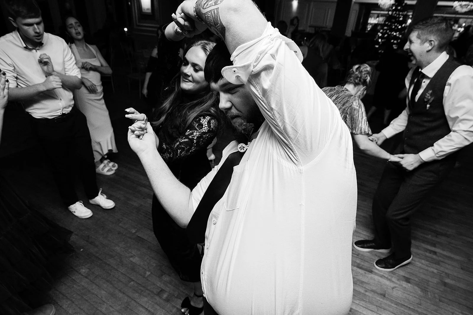 People dancing and having fun at a party, with some holding hands or dancing closely together.