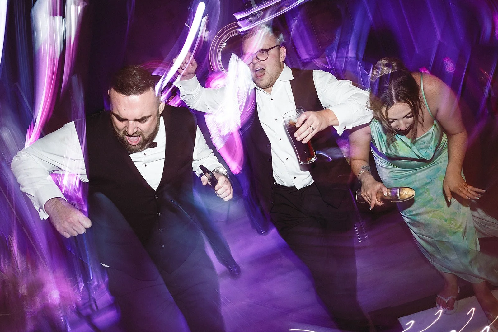 People dancing at a party with colorful, streaked lighting effects.