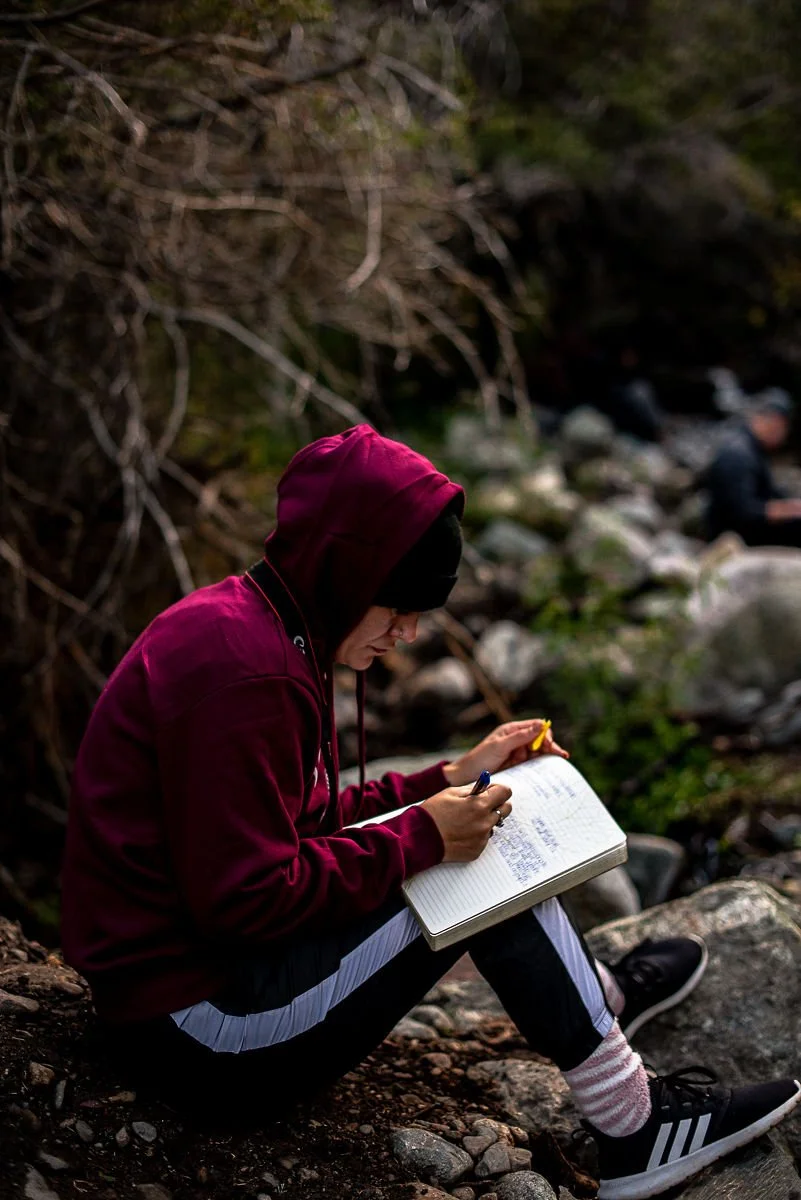 Young female journaling by the river.