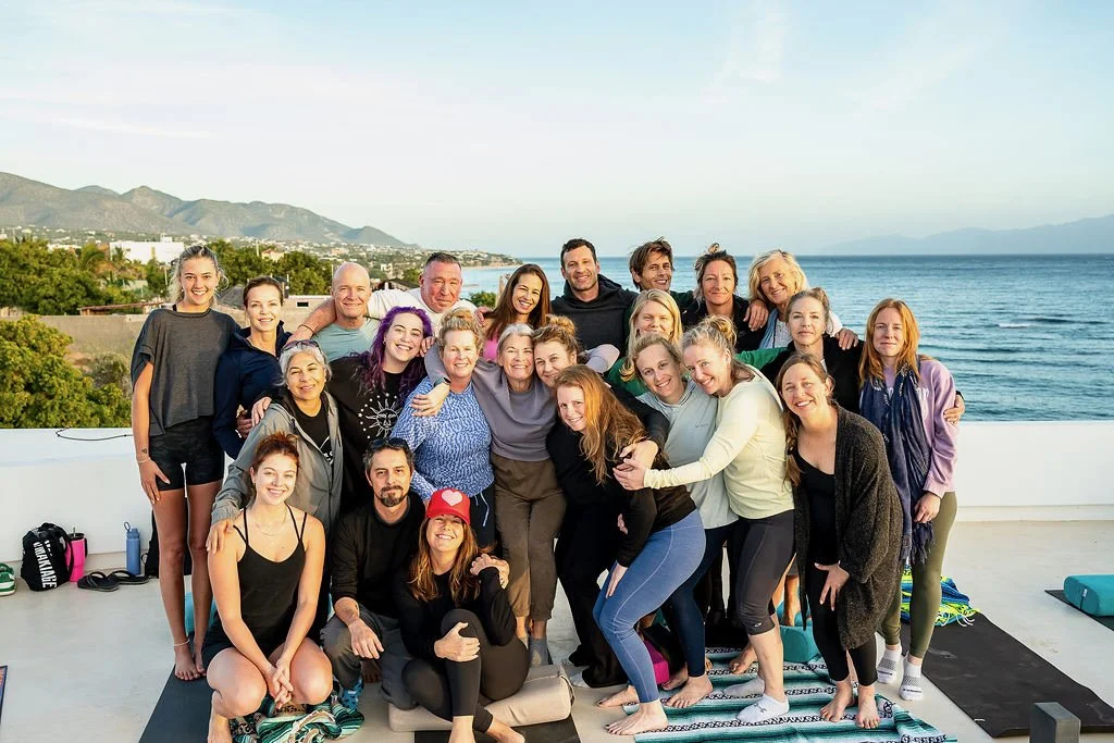 Person relaxing in a hammock on a porch, watching the sunset over a desert landscape with sparse bushes and cacti.