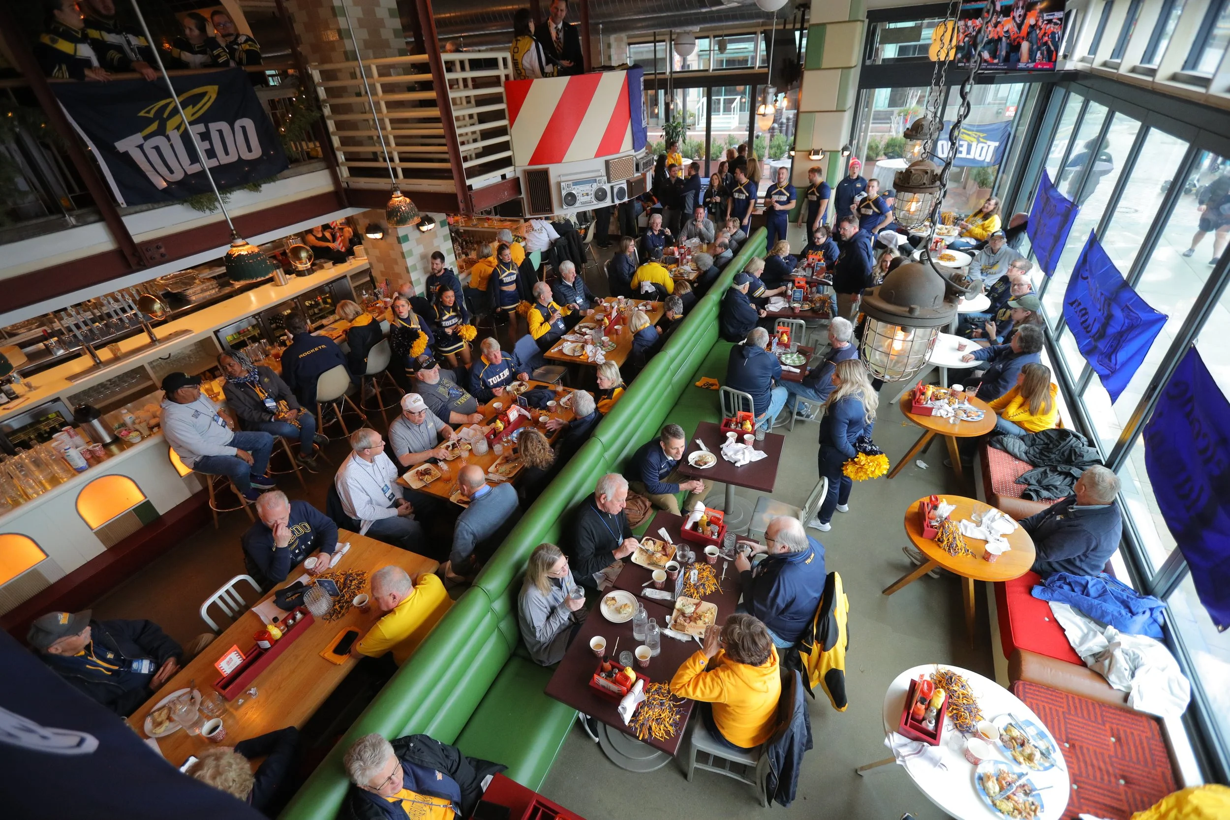 A busy restaurant of people talking at tables during an alumni event. 