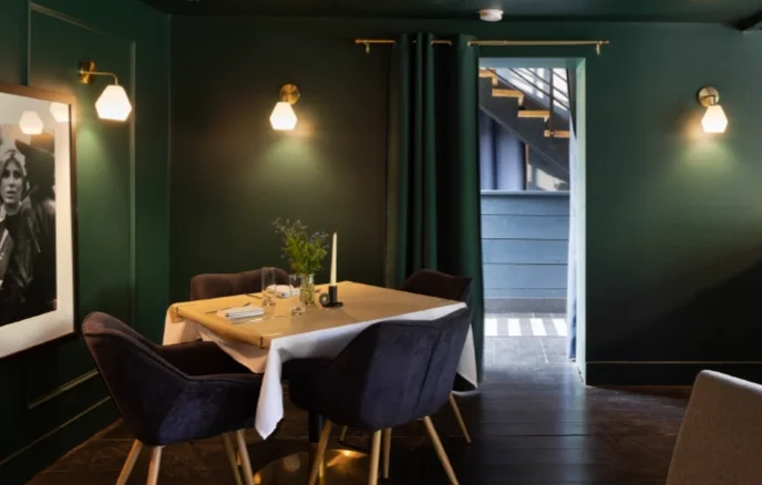 Elegant restaurant dining room with dark green walls, velvet chairs, and ambient lighting at a Catskills boutique hotel.