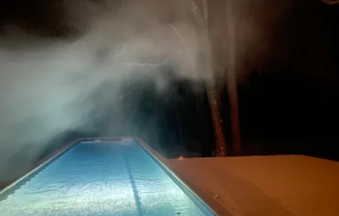 Heated outdoor pool at night with steam rising in a secluded Catskills boutique hotel setting.
