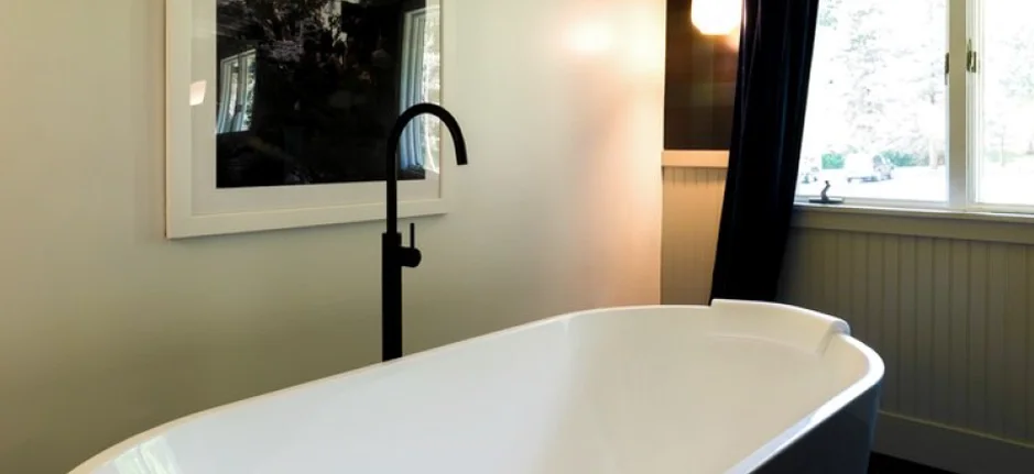 Modern freestanding bathtub inside a luxury boutique hotel room in the Catskills with natural lighting and minimalist decor.