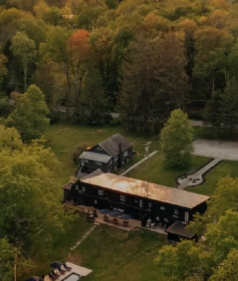 Aerial view of a boutique hotel property surrounded by forest and open land in the Catskills.