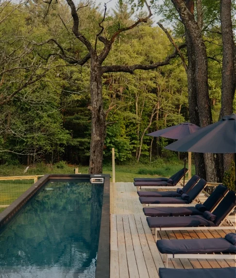Heated outdoor pool at night with steam rising in a secluded Catskills boutique hotel setting.