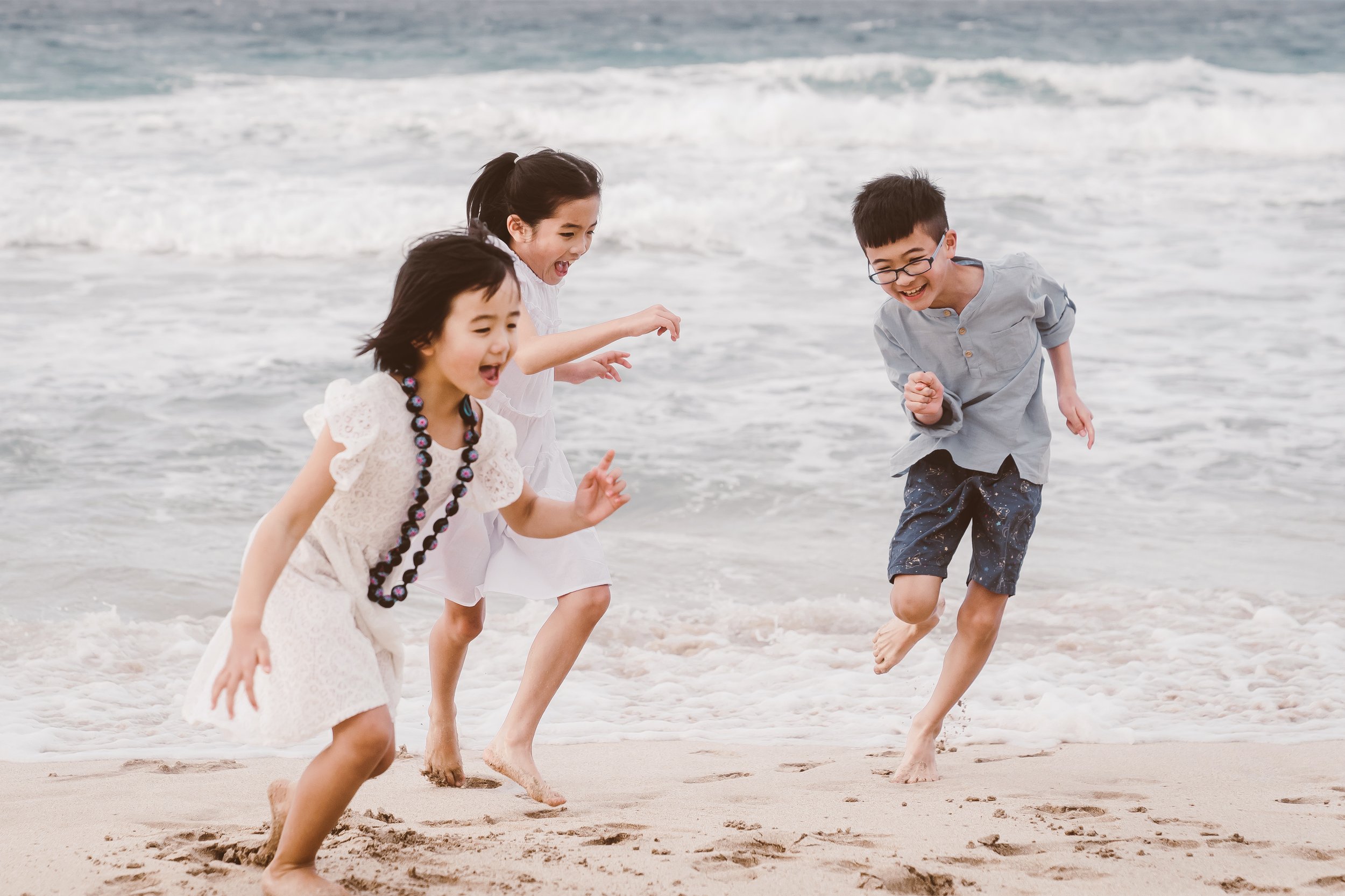 Professional maui photographer takes photos of children playing on the beach at sunset in Maui HI