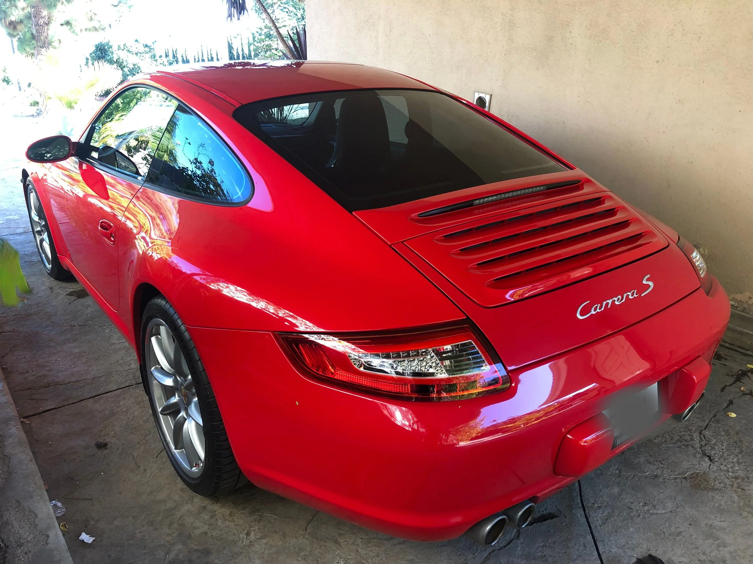 Red Porsche Carrera S sports car parked in a garage.