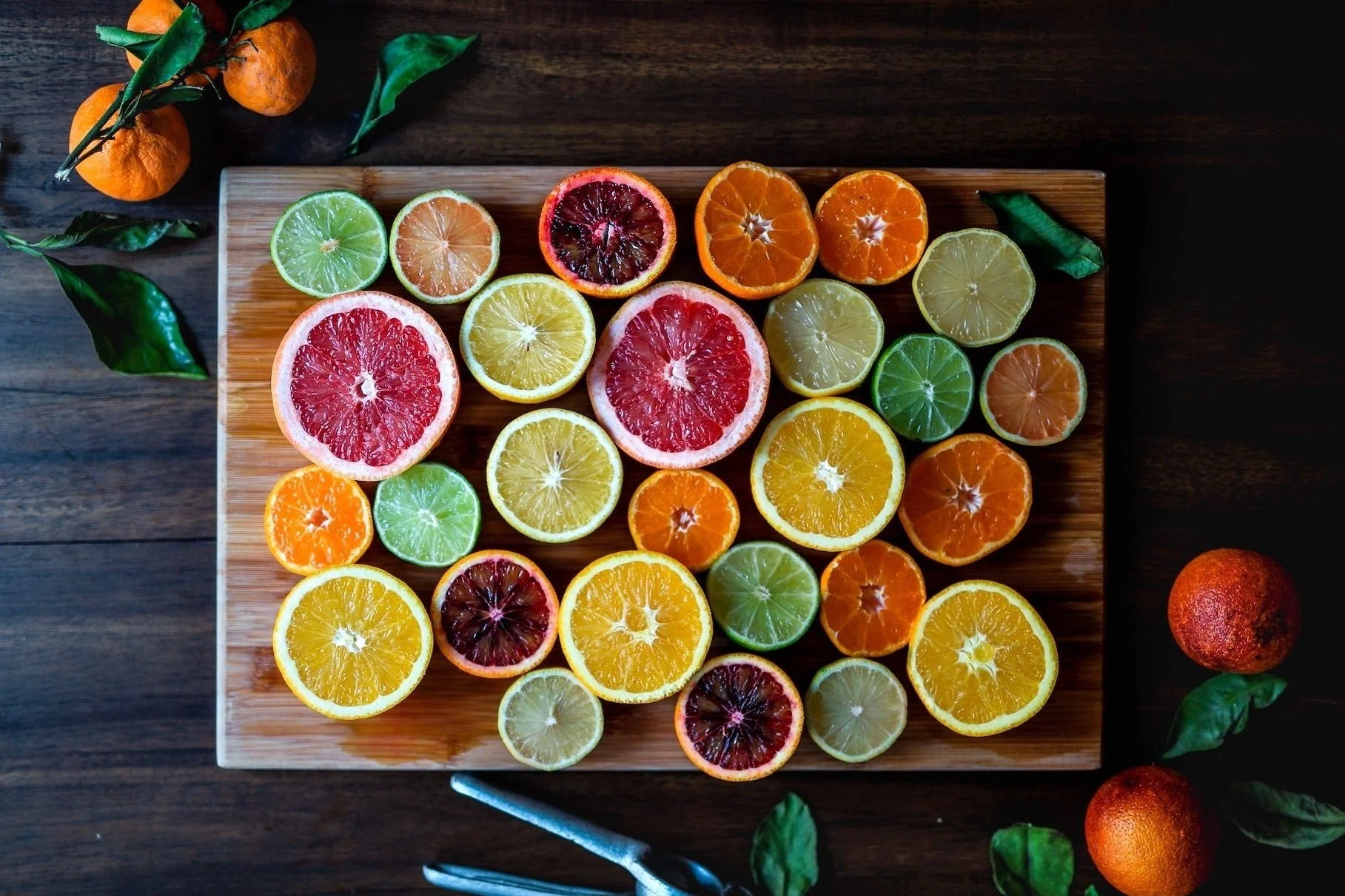 brightly colored citrus fruit halves on wooden cutting board