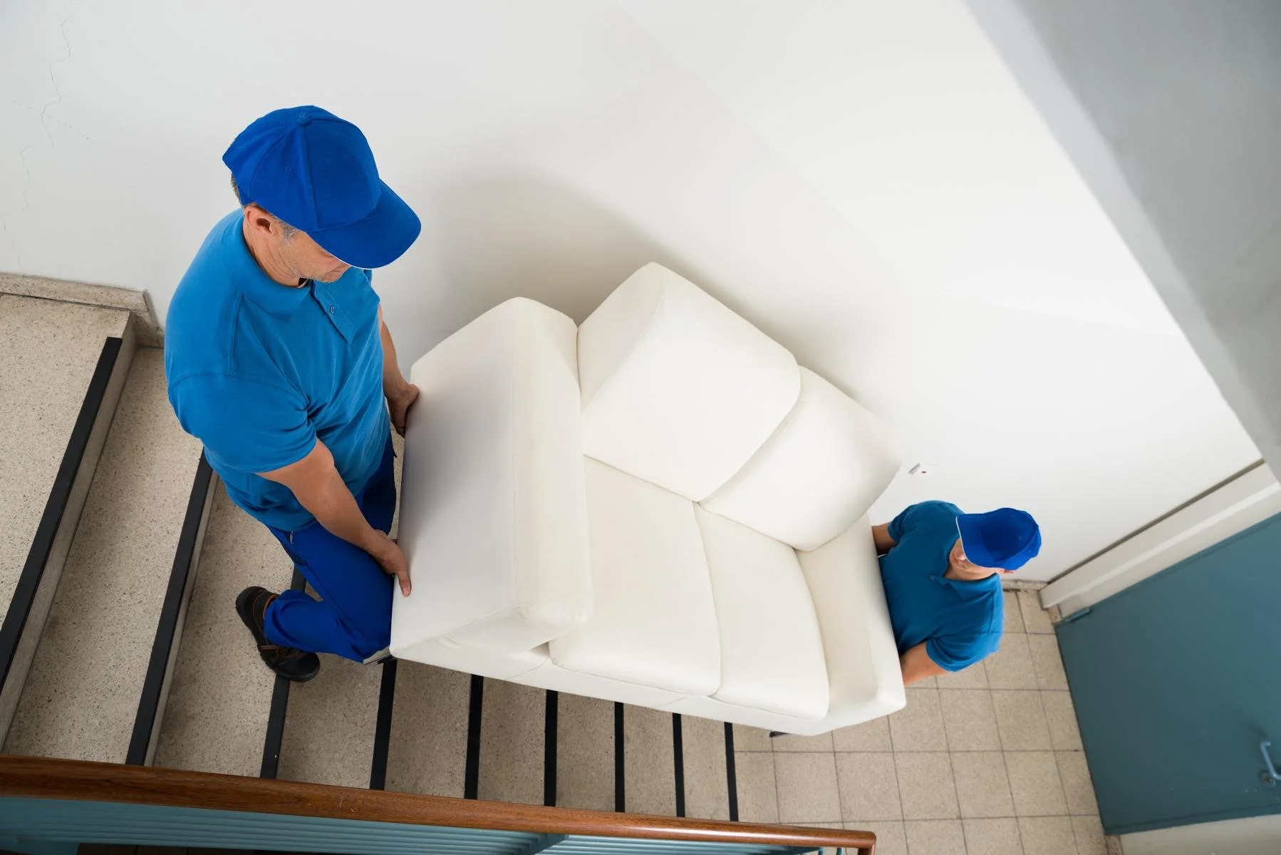 kip Moving - Professional Movers Safely Transporting a heavy white couch downstairs.