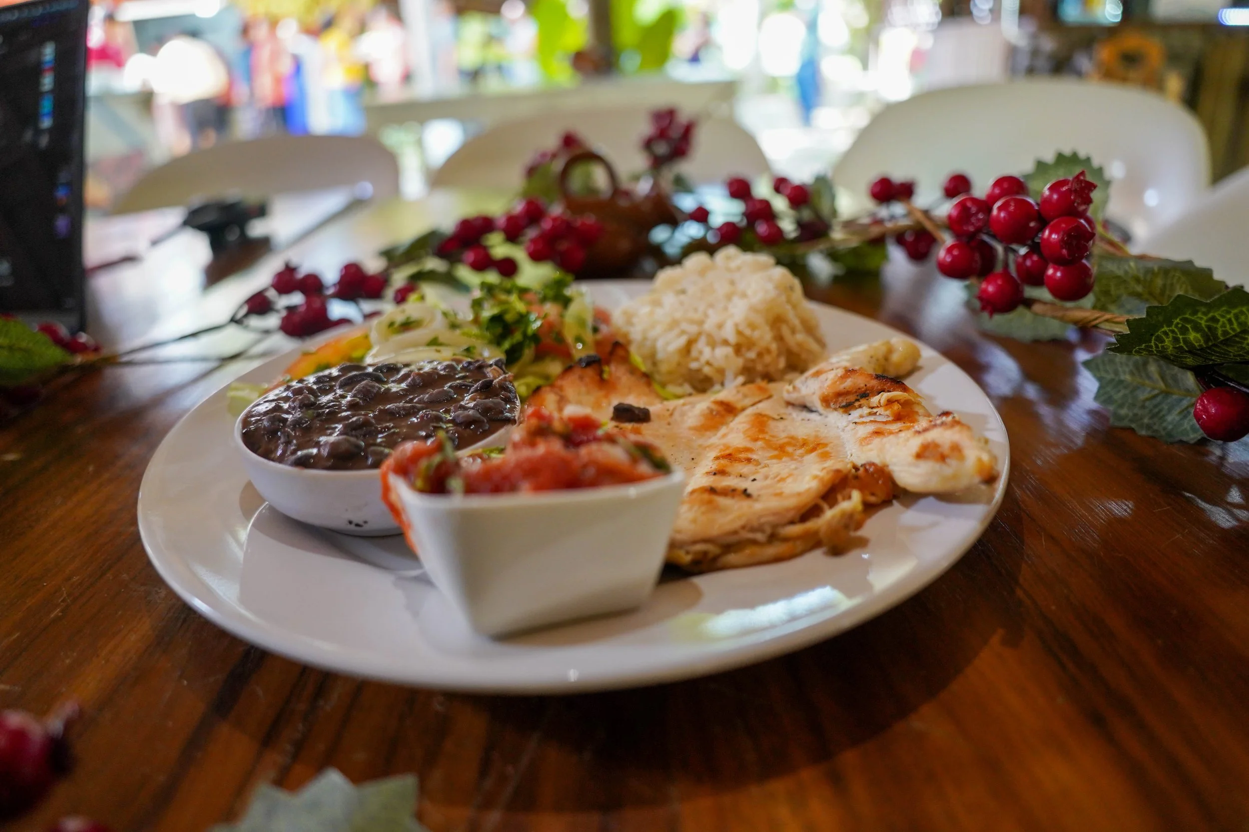 Plato con frijoles negros, ensalada, pollo a la parrilla, arroz y salsa