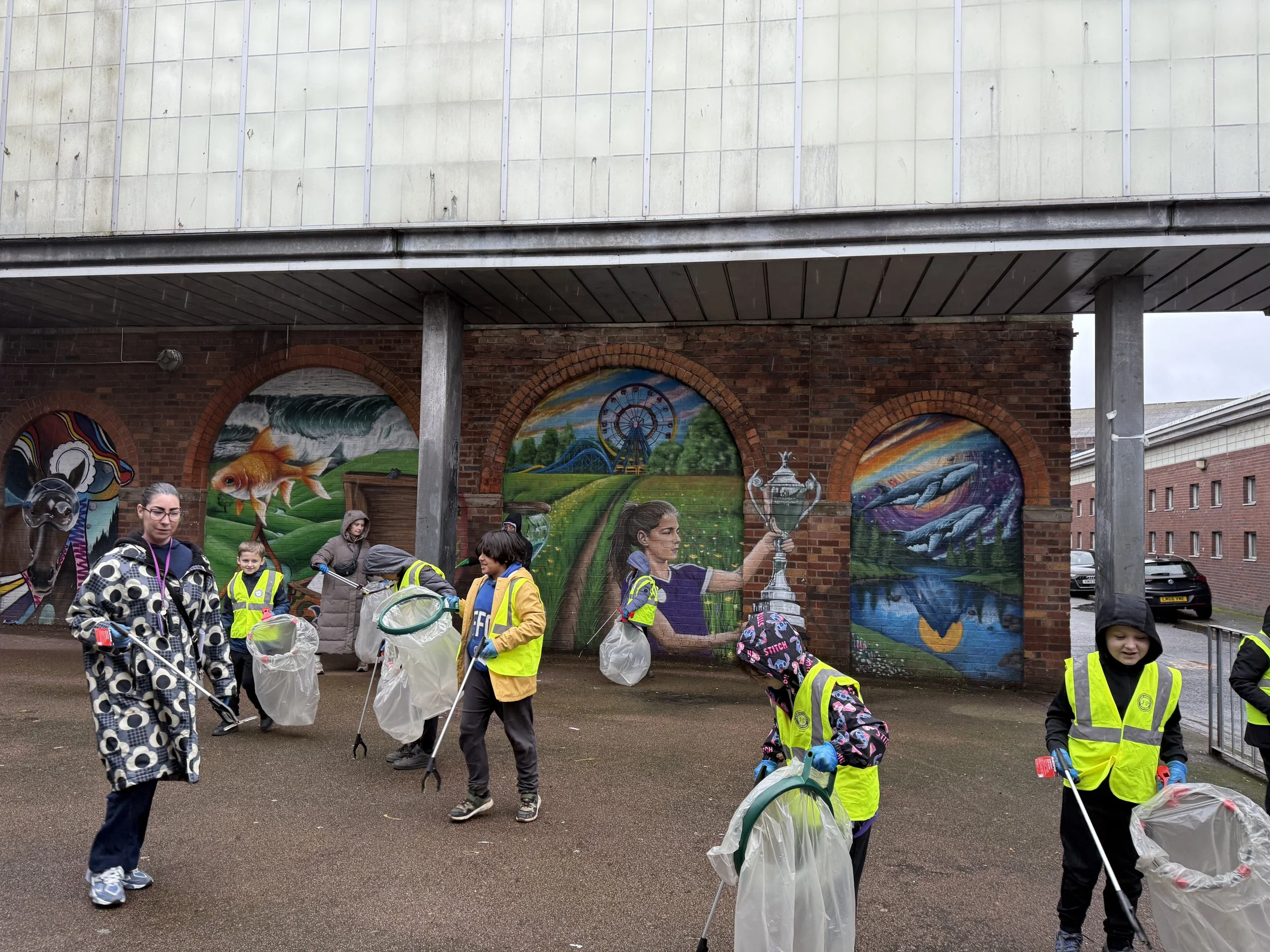  Children litter picking up litter in front of mural 