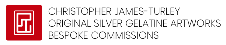 Close-up of a red and black logo with a stylized maze pattern.