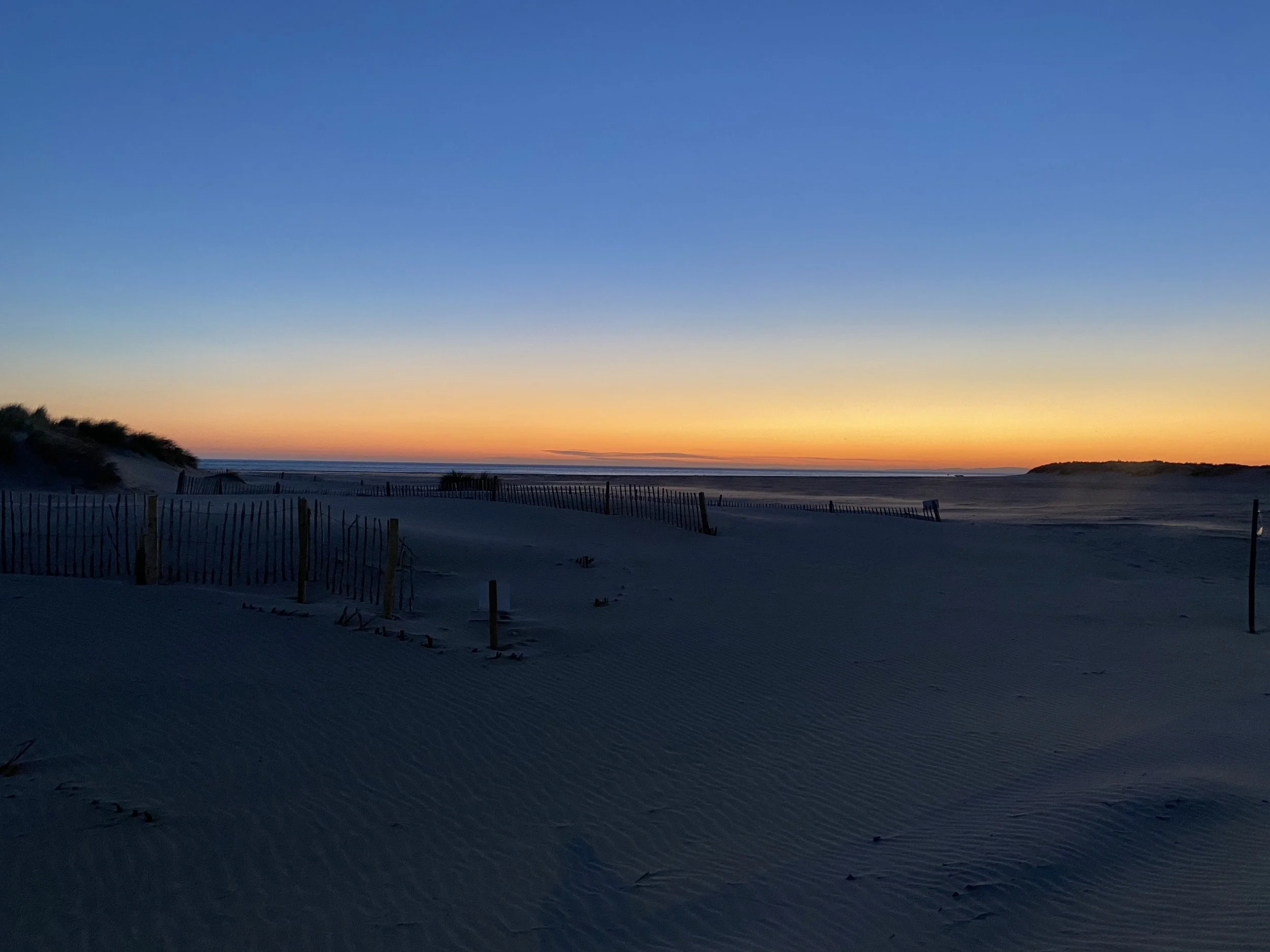 Sunset over the beach at Barmouth, Wales with dark blue sky and deep orange sunset