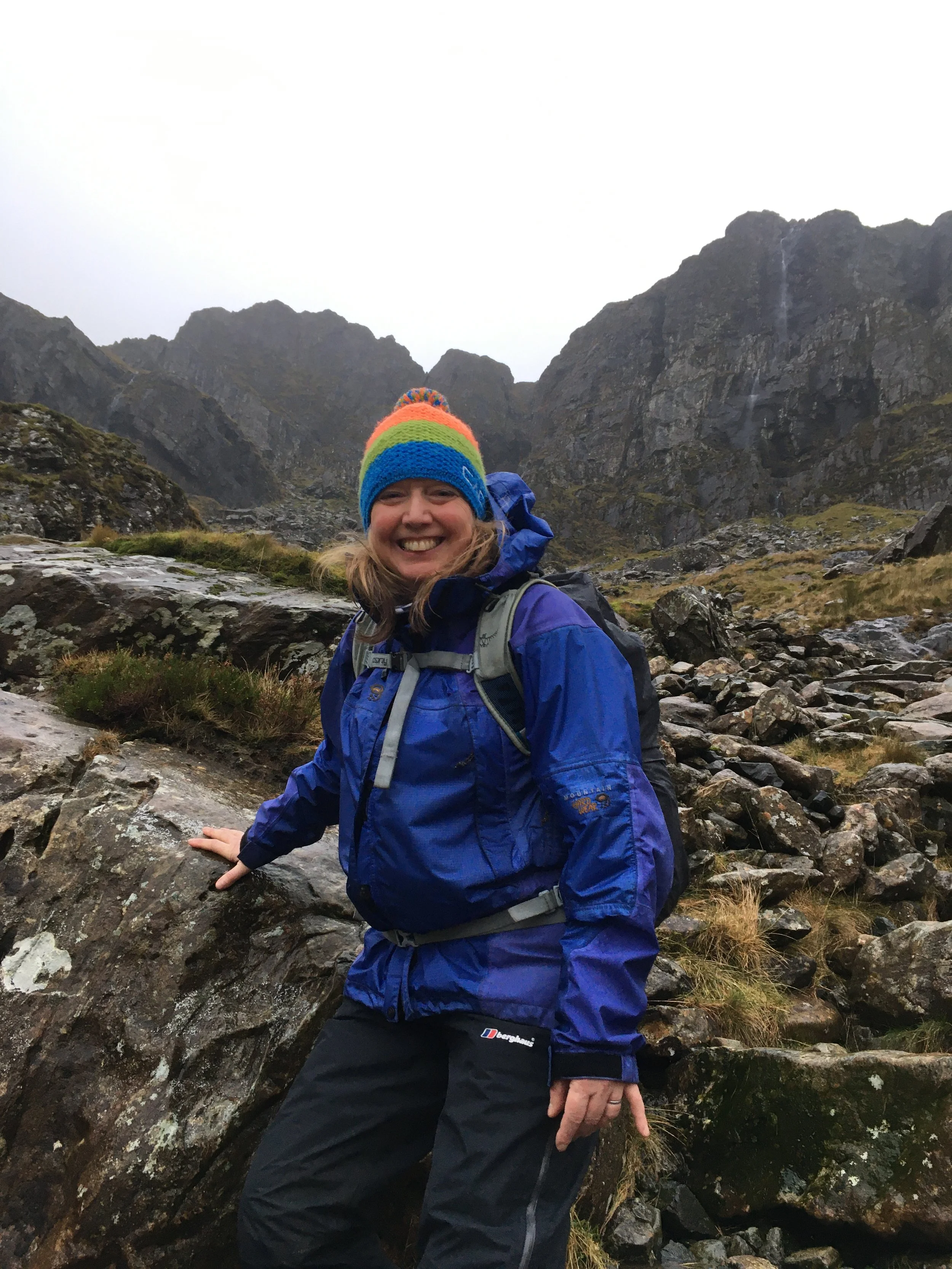 Jacquie Budd standing in front of the Idwal Slabs in Snowdonia, wearing a blue waterproof jacket