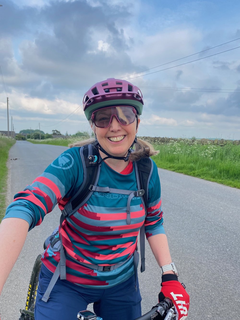 Jacquie Budd wearing a cycling helmet, cycling on West Yorkshire road
