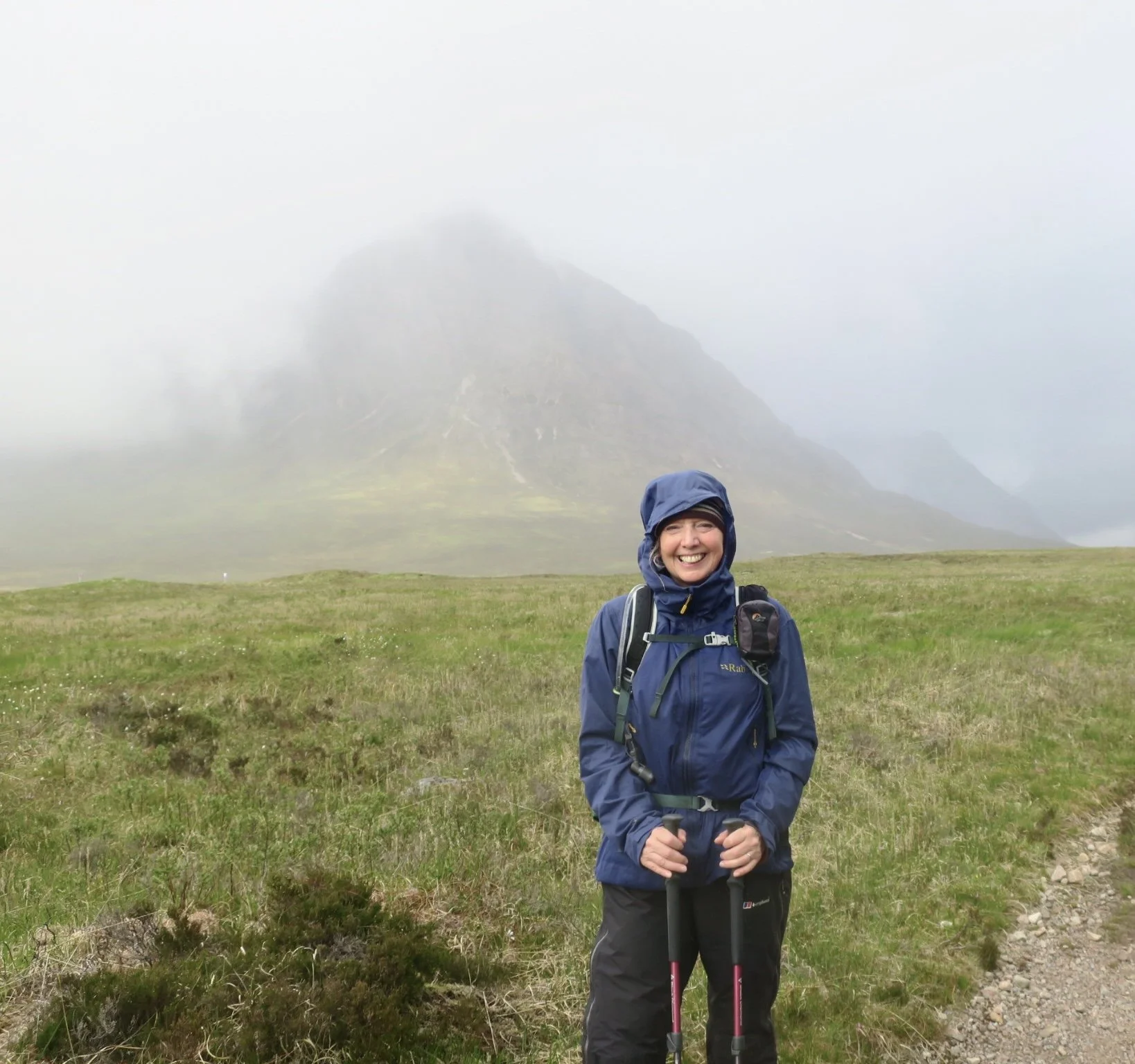 Jacquie Budd standing in front of Buachaille Etive Mòr, shrouded in fog, in Glencoe, Scotland.