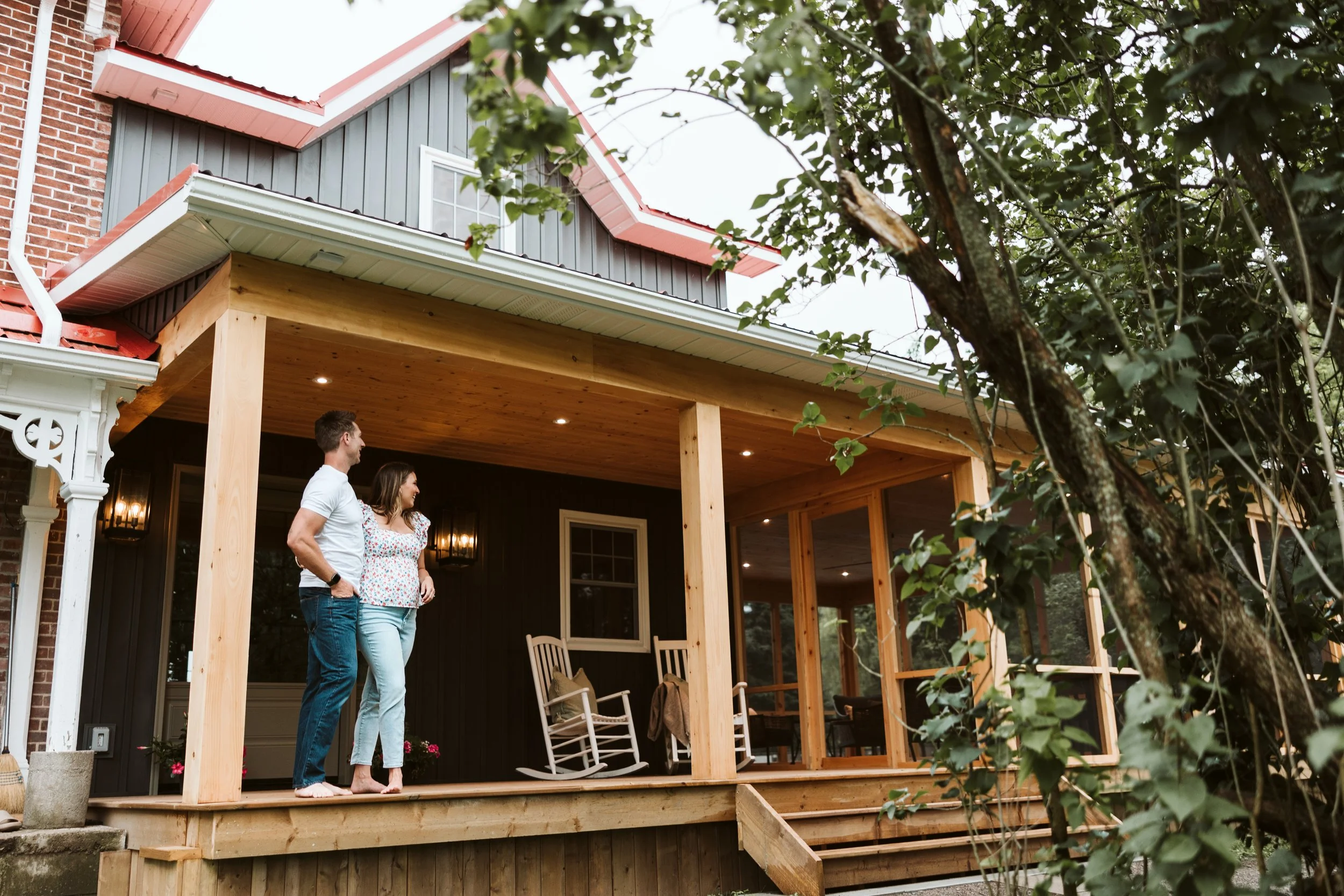 Park Road Design & Build owners, Monique & Andrew standing on the porch addition of a newly renovated century home