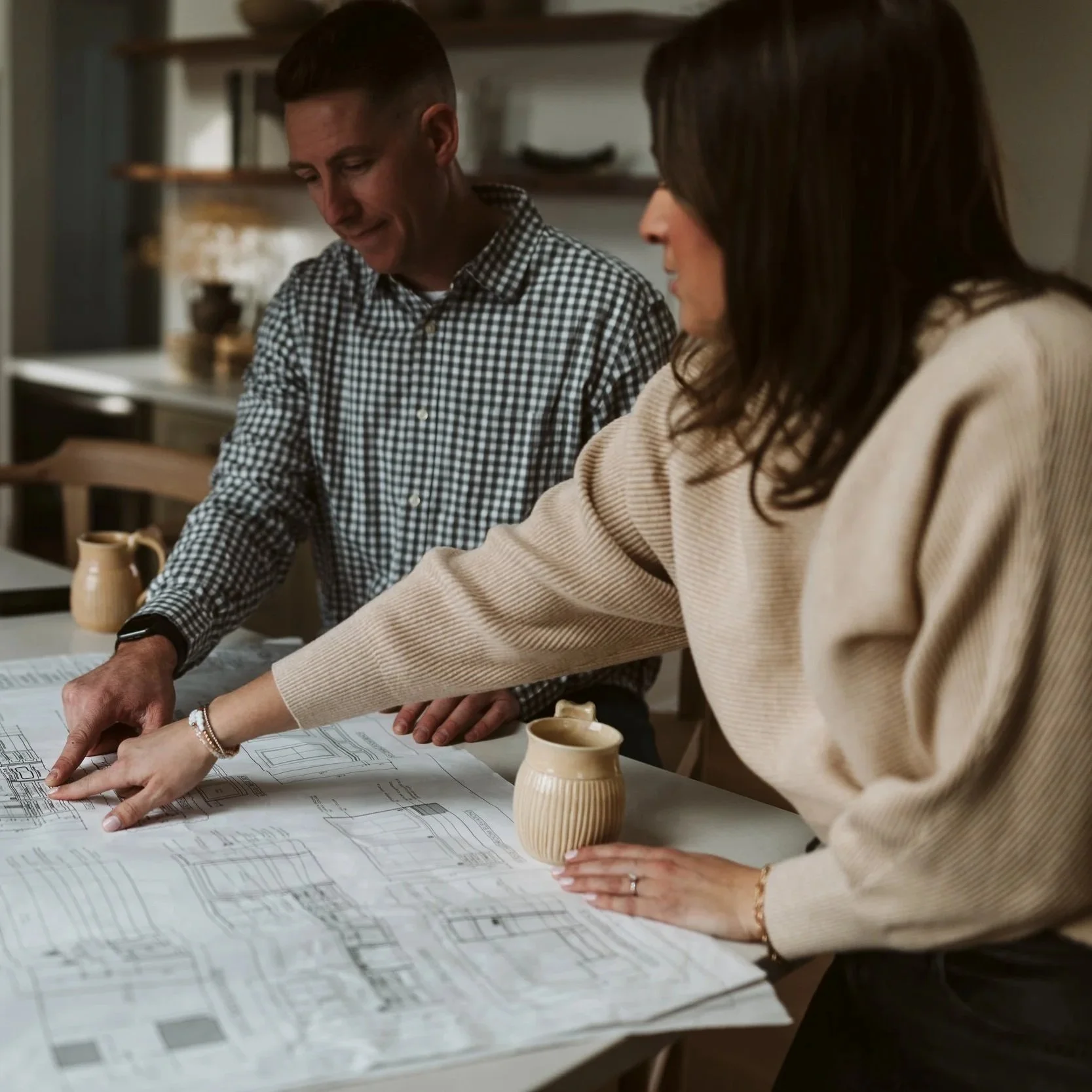 Owners of Park Road Design & Build pointing at a floor plan for a farmhouse renovation