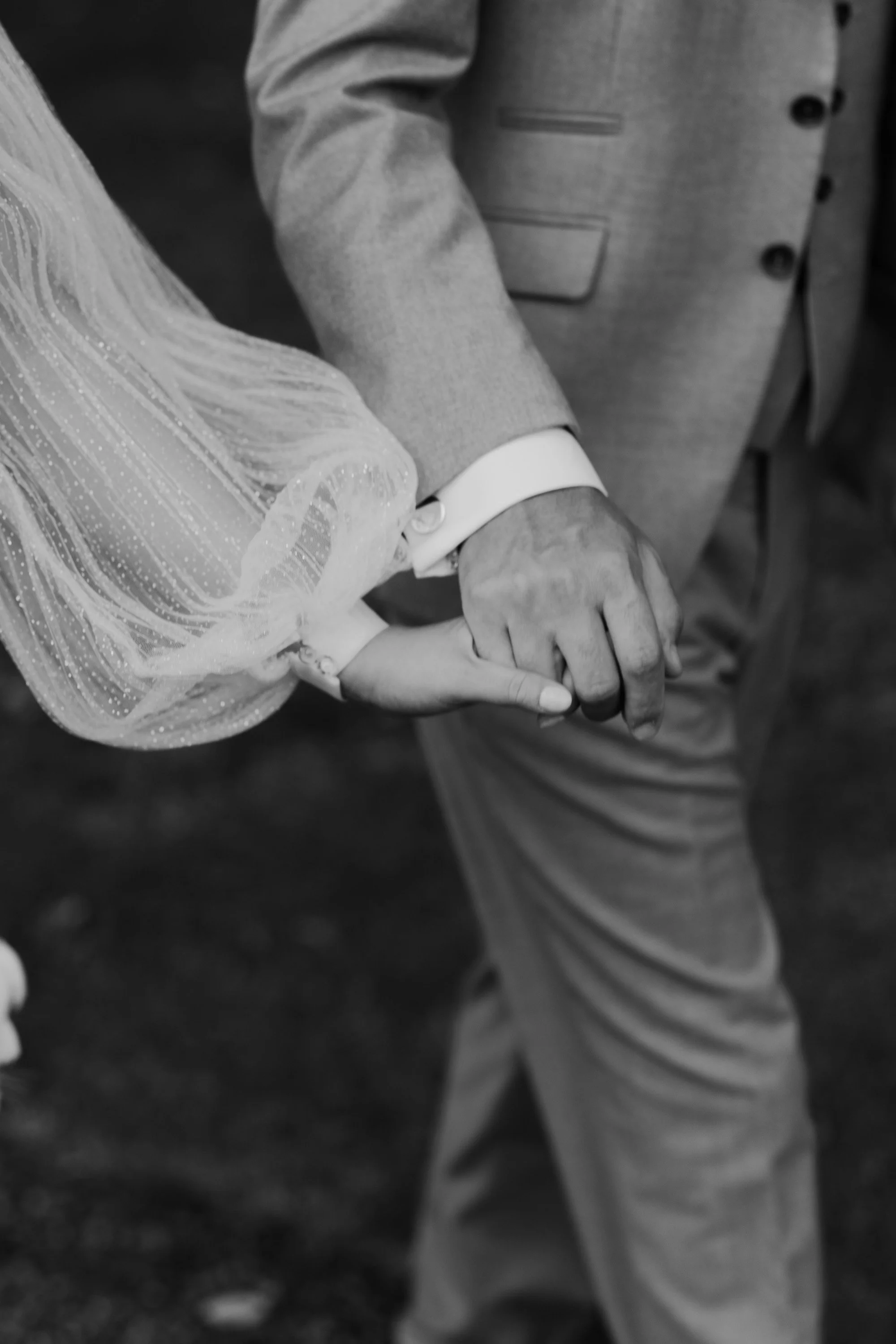 Black and white wedding photo of couple holding hands