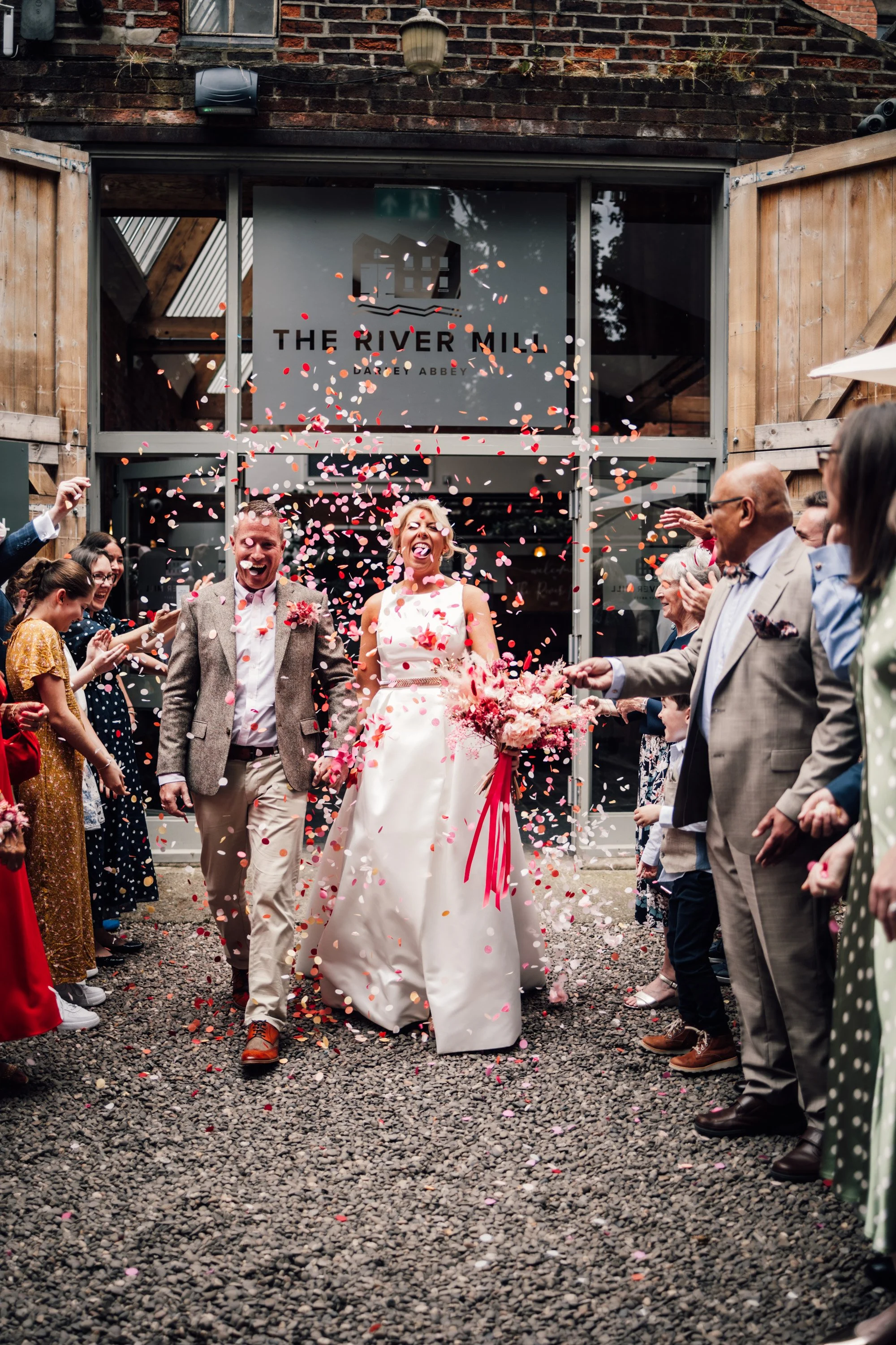 Paper confetti shot with red, pink, and white colours at outdoor wedding
