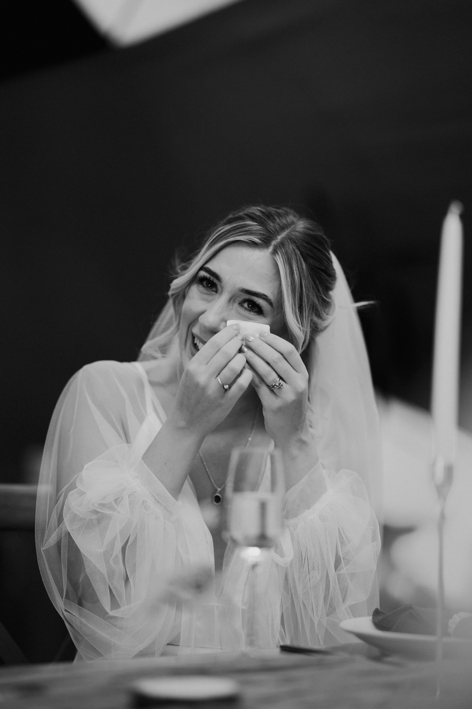 Black and white photo of bride wiping tears away during speeches at a derbyshire wedding