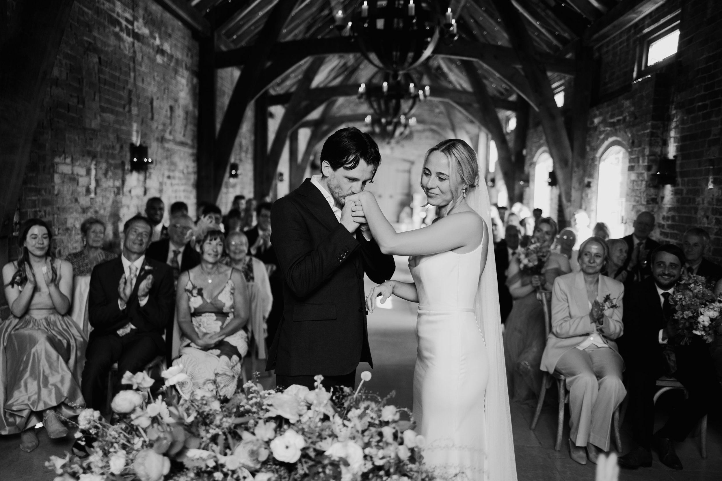 Groom kisses brides hand at the beginning of the wedding ceremony at Cripps and Co wedding venue
