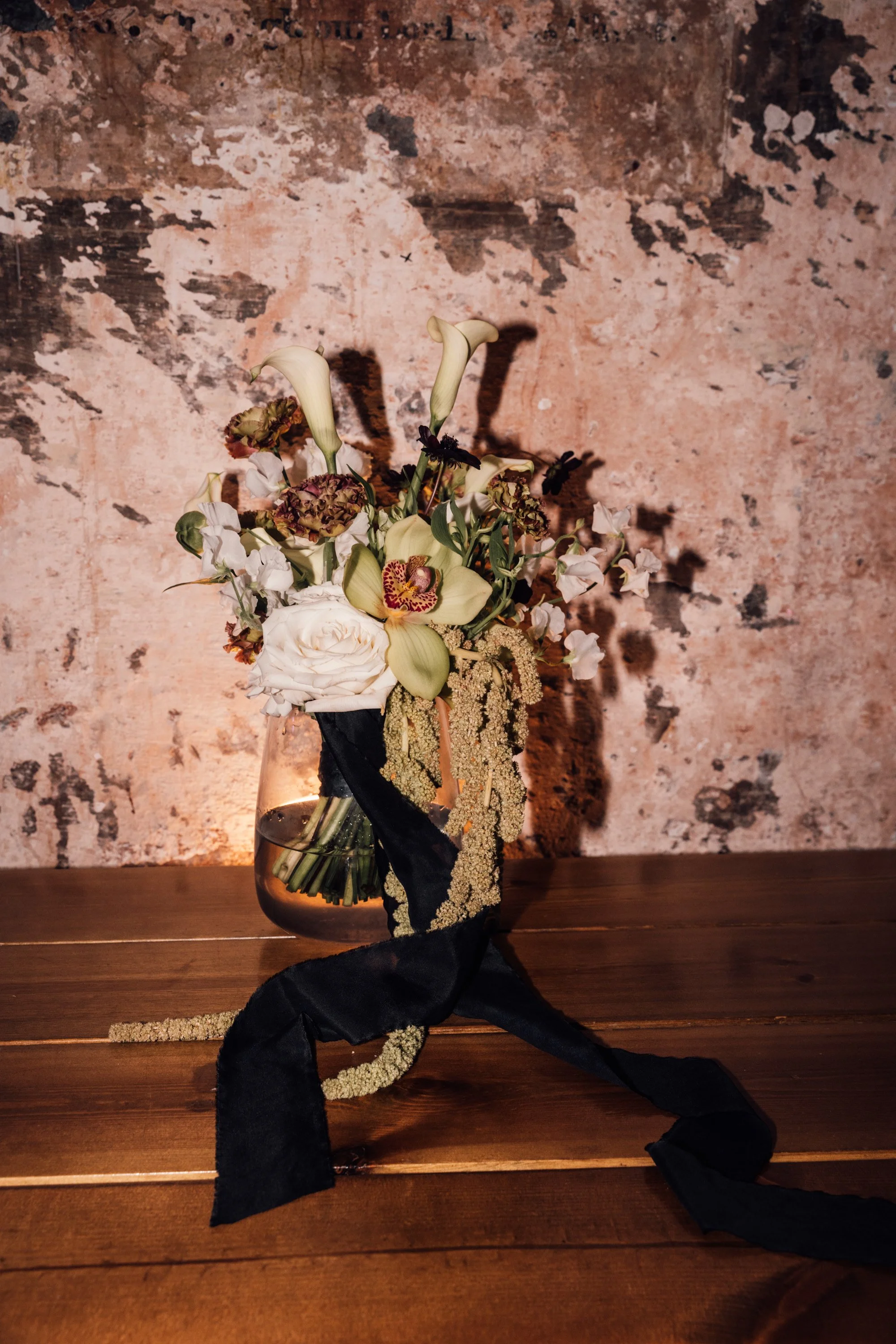 Editorial wedding photography details bridal bouquet with black satin ribbon and roses