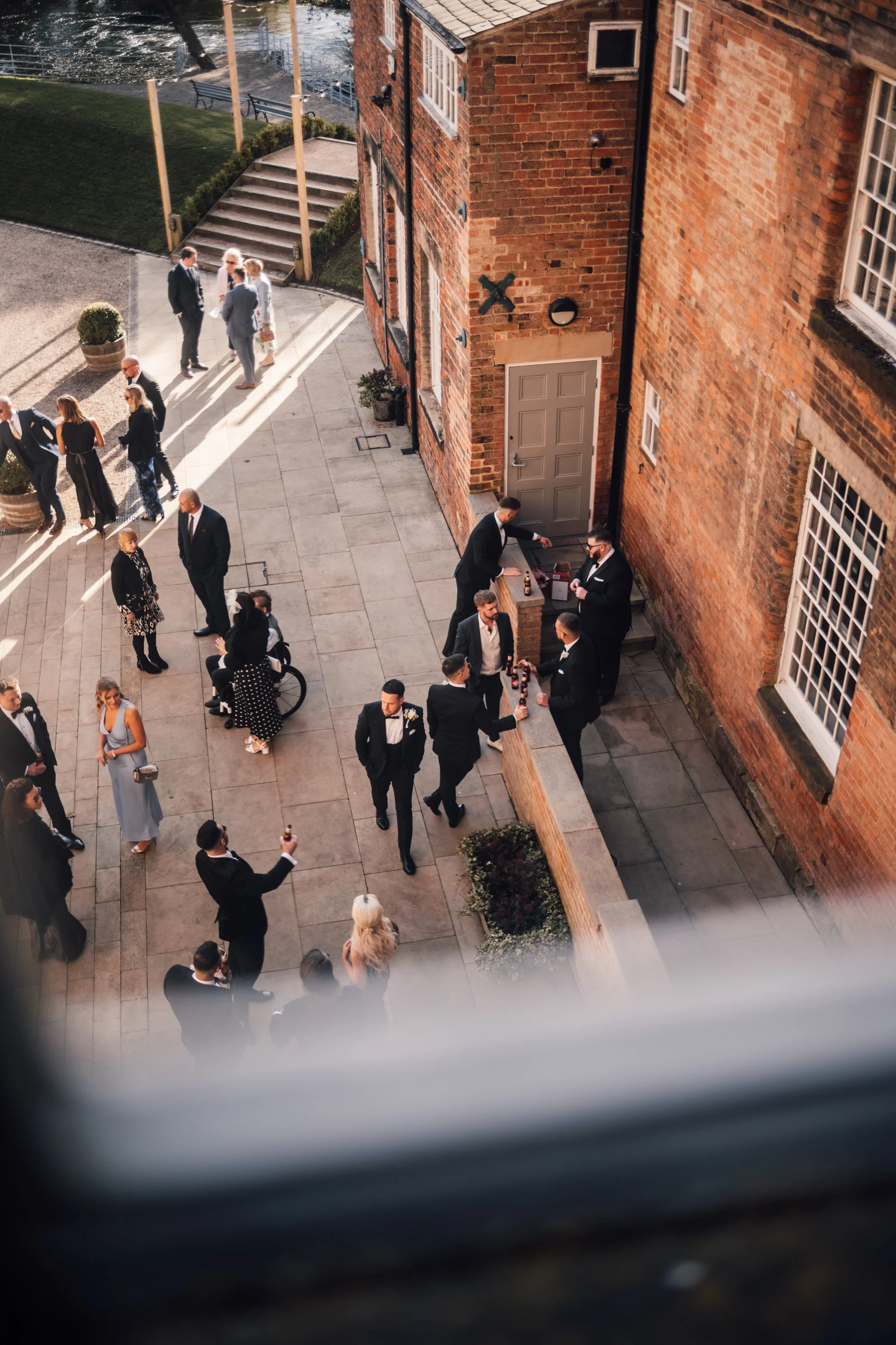 Groom in black tie walking through The West Mill's industrial courtyard