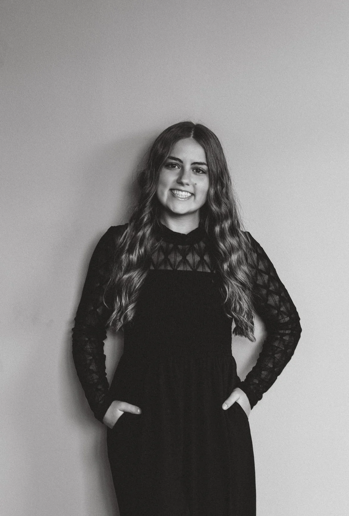 woman in all black on black background smiling at the camera