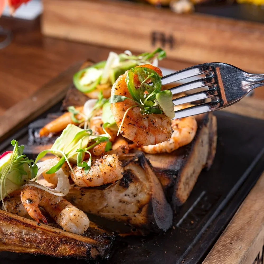 Corte de carne asada con camarones y verduras frescas.