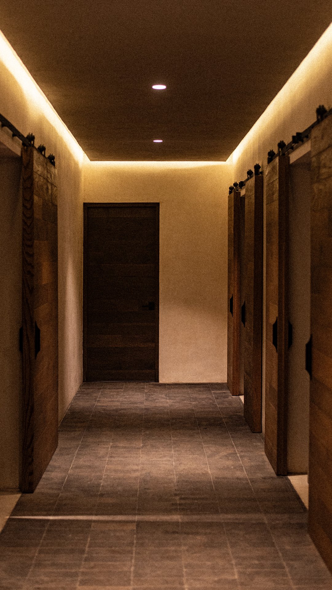 Pasillo con puertas de madera en ambos lados y iluminación suave en el techo