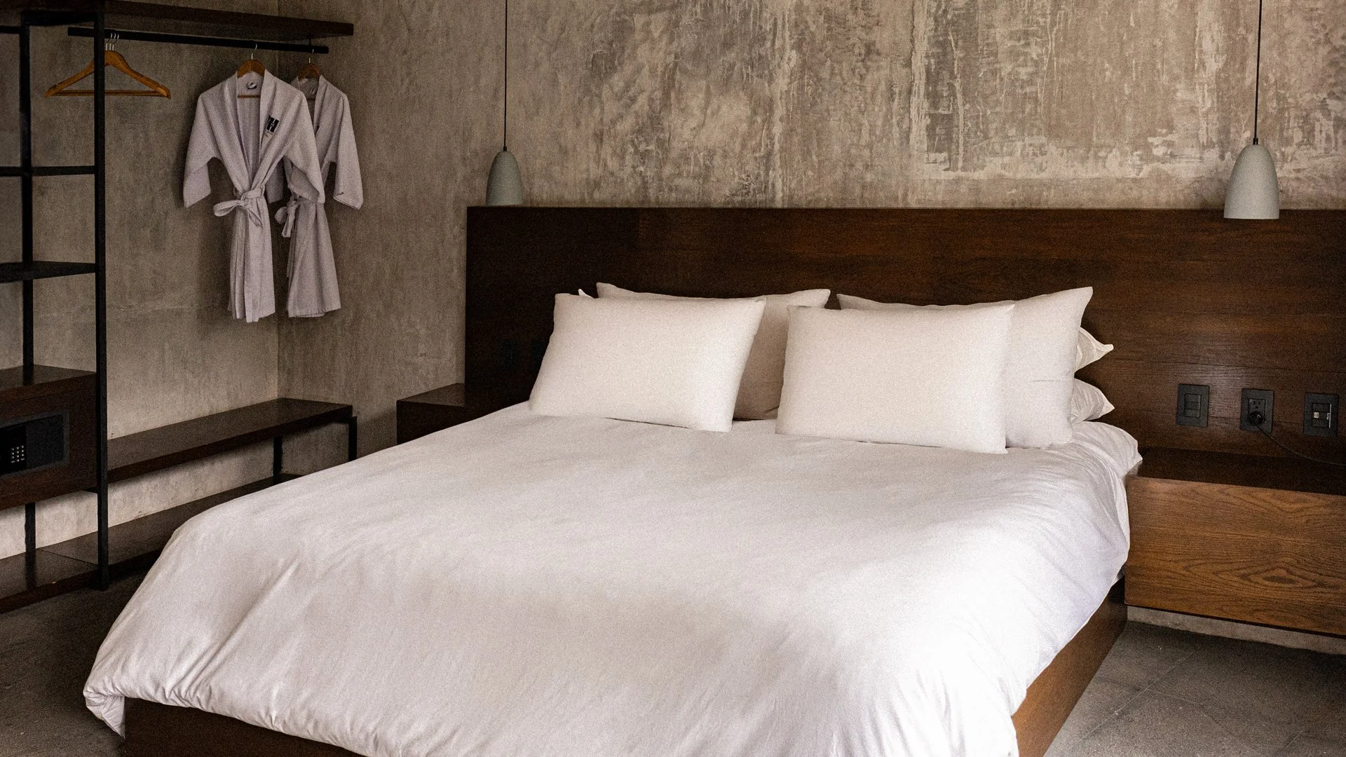 Habitación con cama grande, ropa en toalla en percha y concha de baño, lámparas y enchufes en la pared.