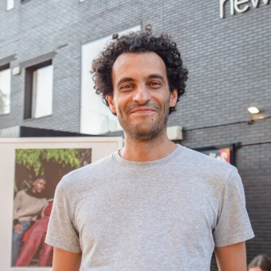 A man with curly hair wearing a grey t-shirt.