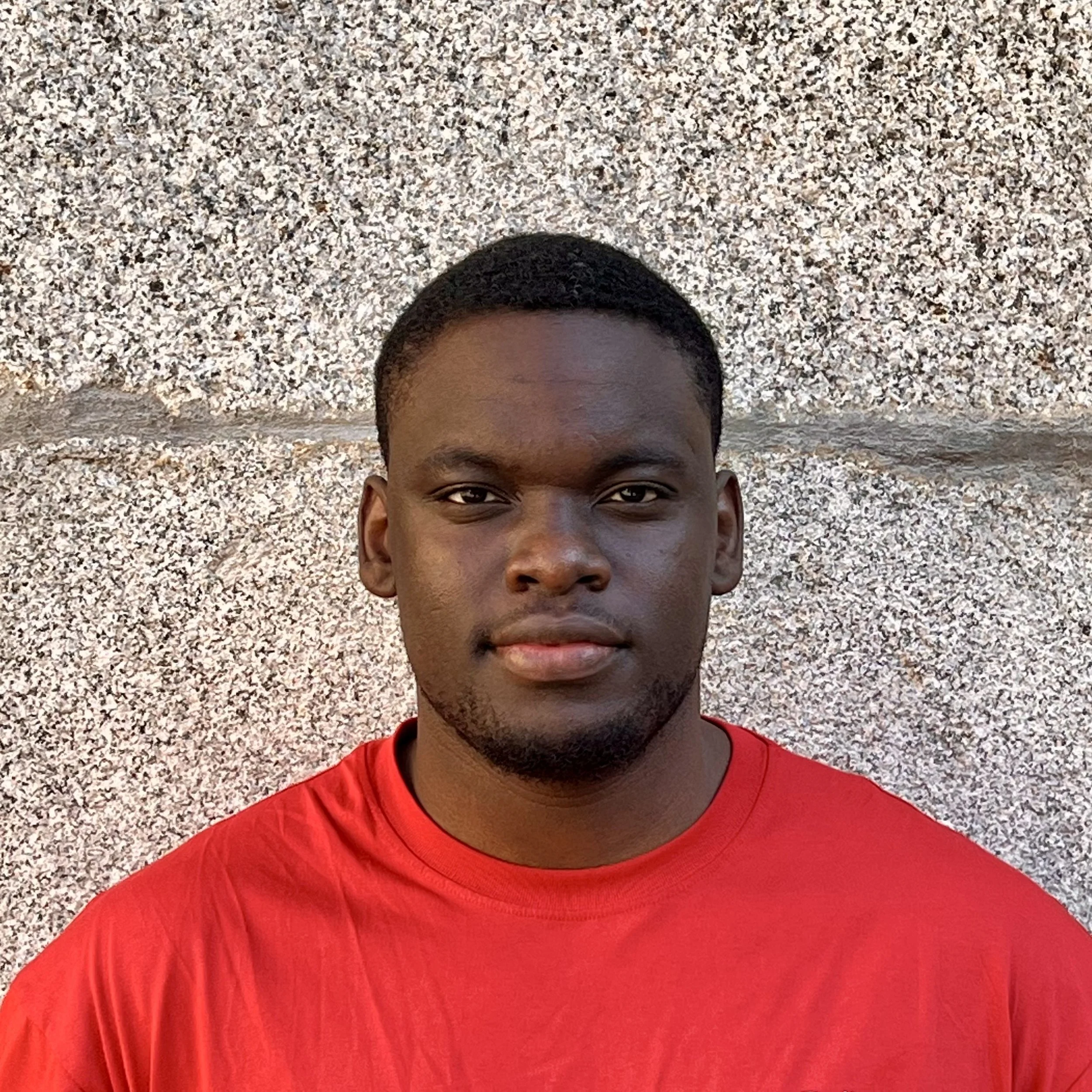 A young black man wearing a red t-shirt.