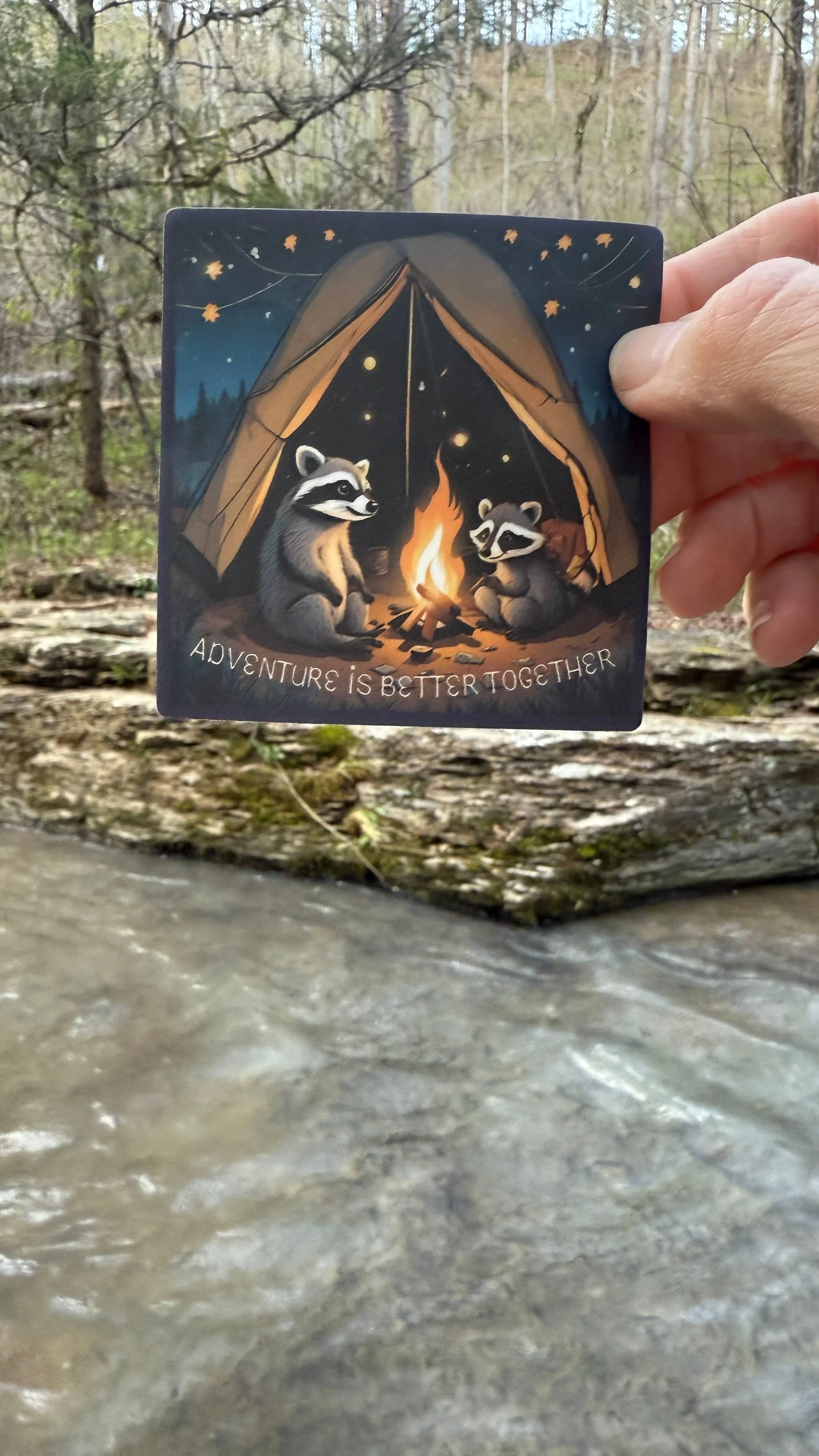 Raccoon family camping in a tent behind a campfire