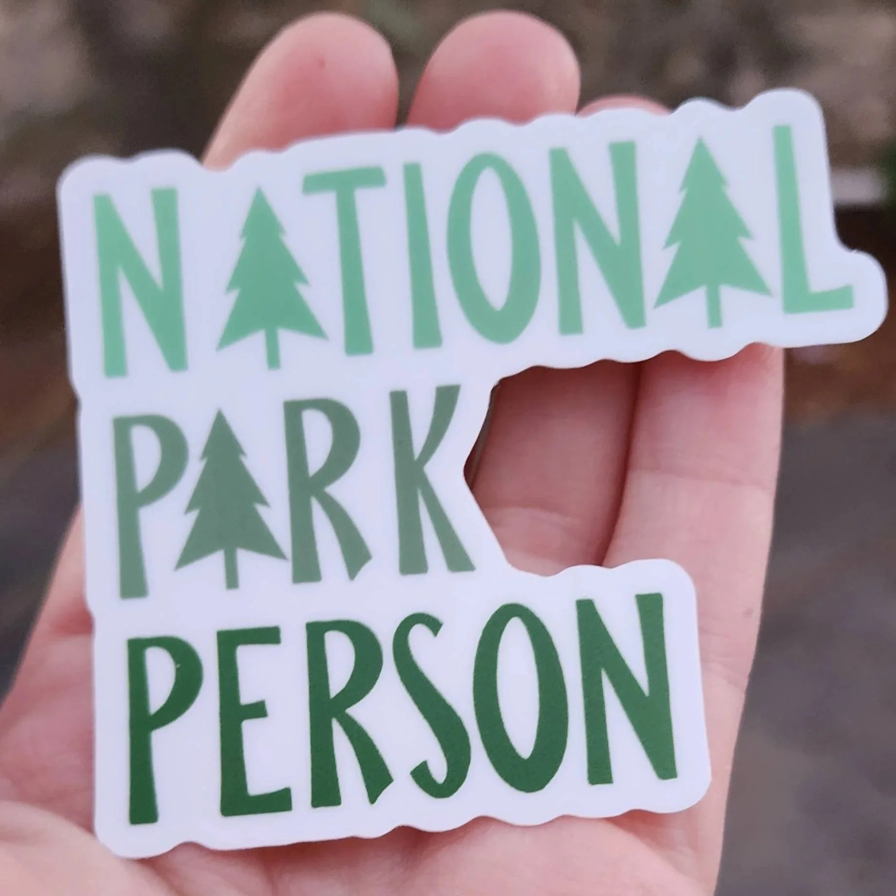 National Park Person Green and White Sticker in the palm of a hand