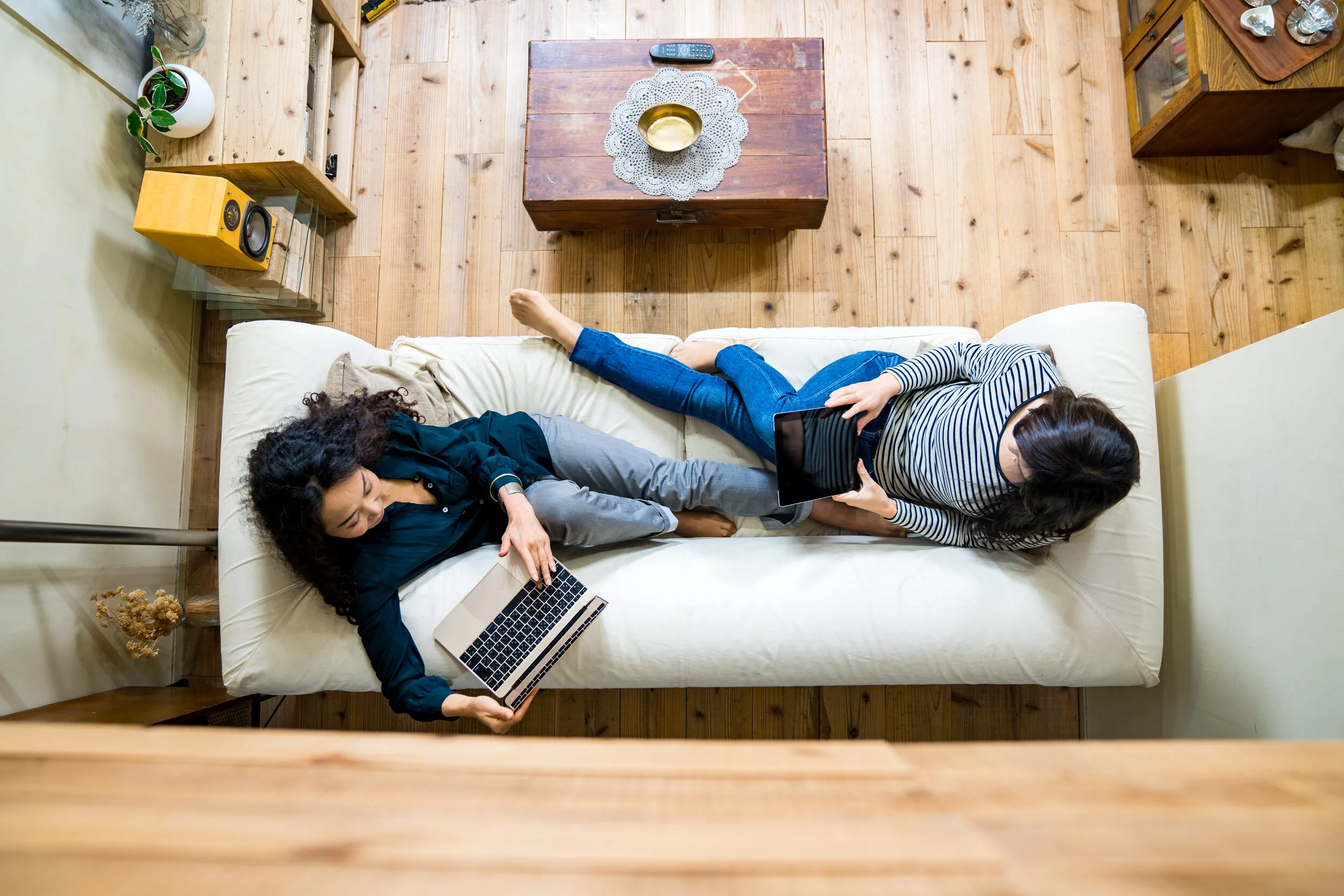 A top down view of two ladies sitting on a cozy sofa