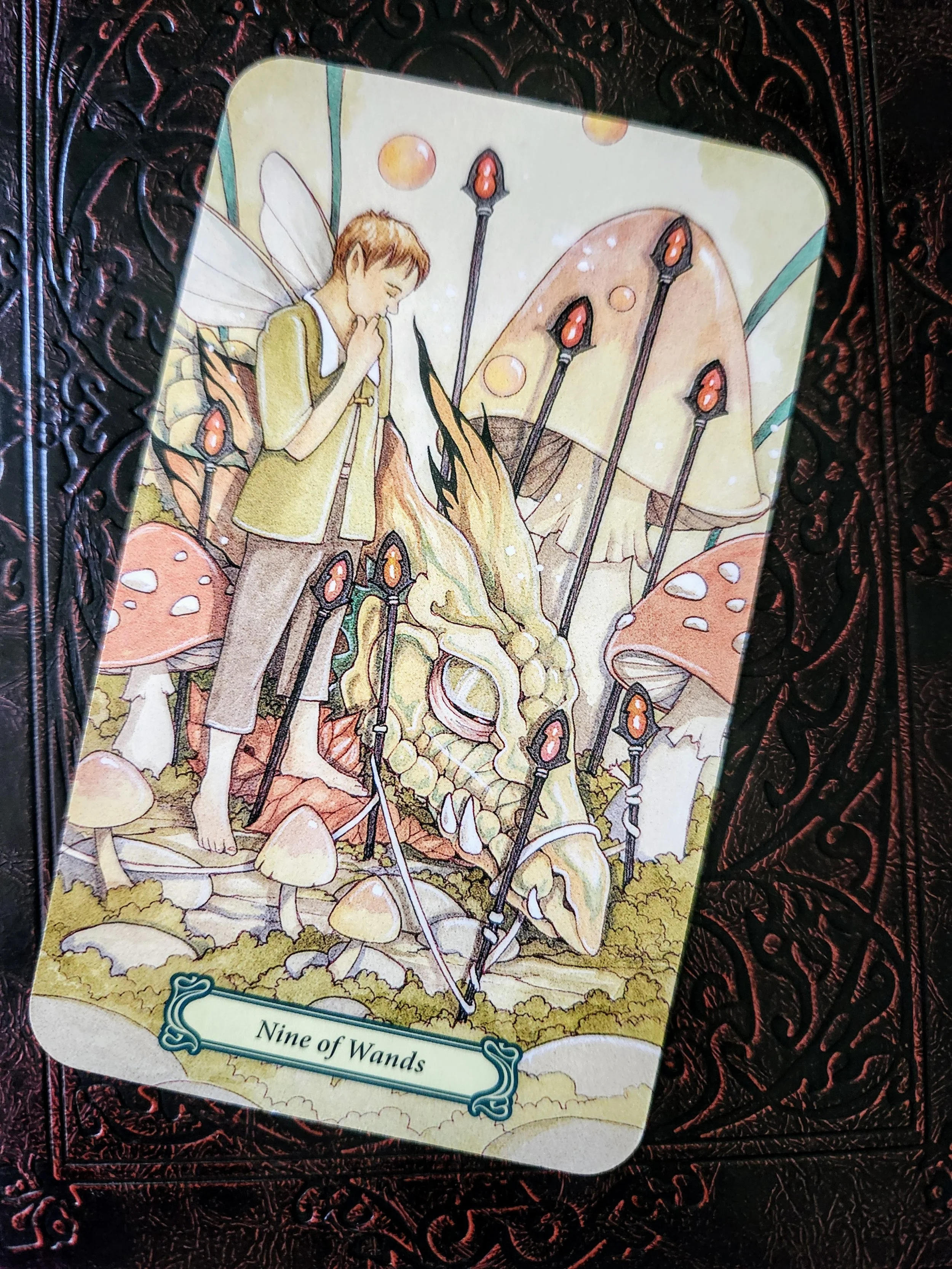 Nine of wands tarot showing a fae figure and resting dragon behind glowing wands - symbolizing emotional endurance, relational trauma, and the guarded strength of neurodivergent survivors.
